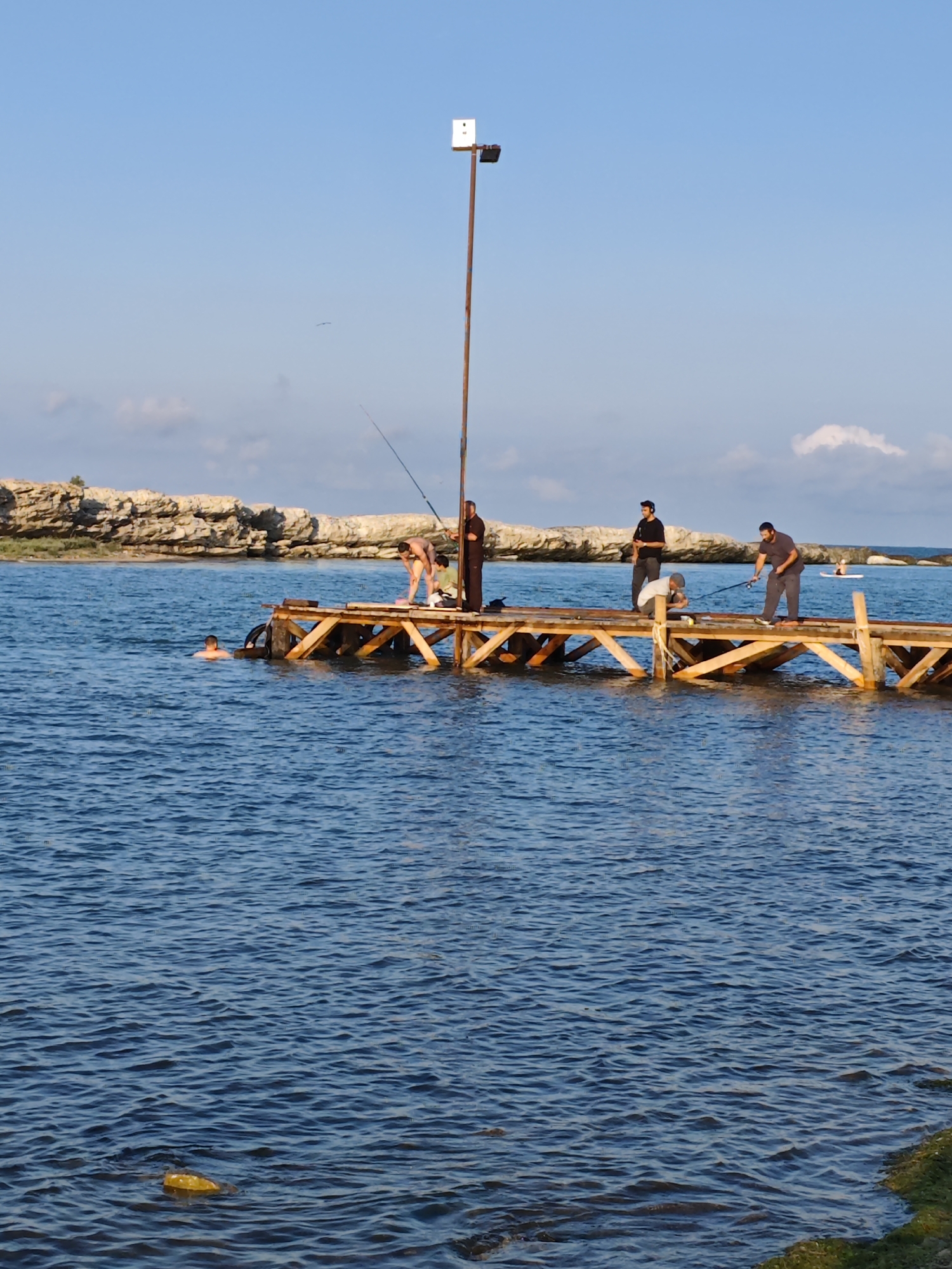 Caspian shoreline life in Izberbash — fishing, cairns, summer afternoon