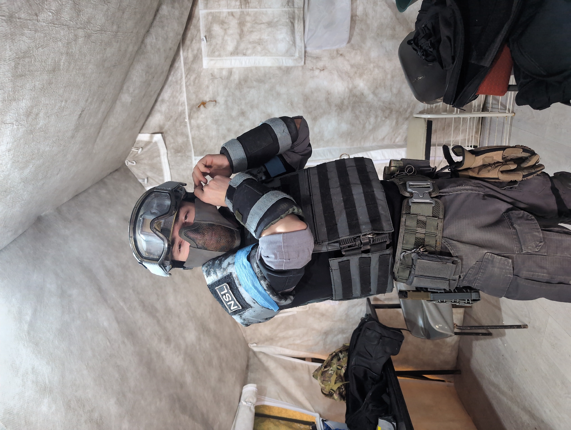 Tactical gear-clad person adjusts equipment indoors in Izhevsk