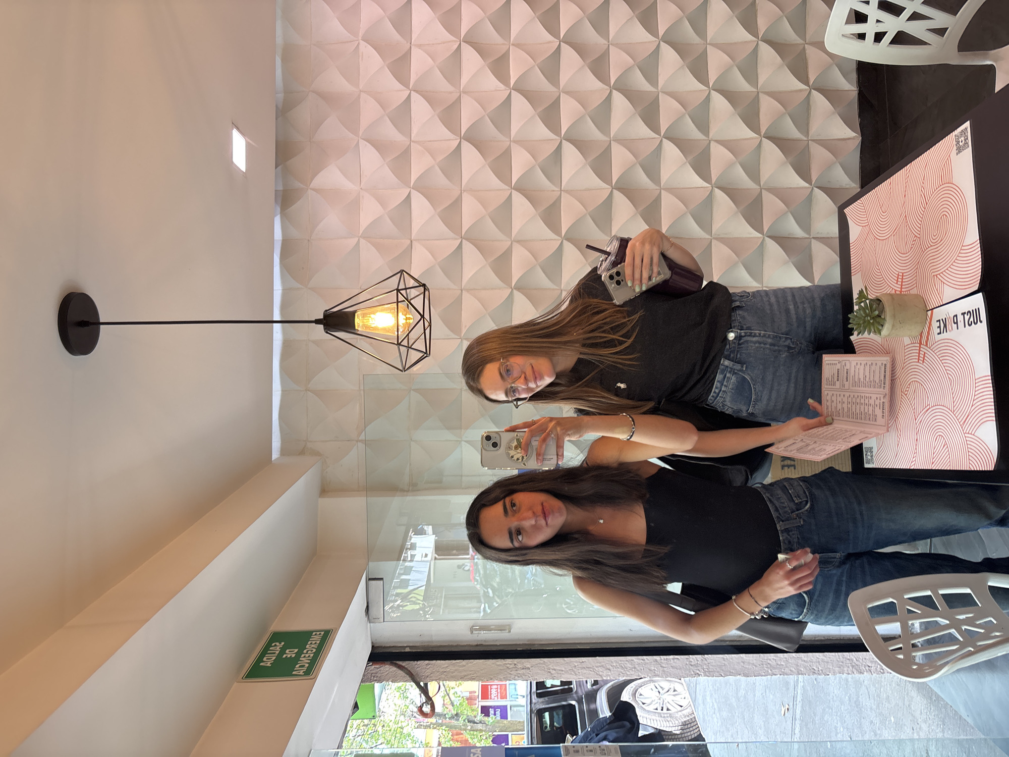 Two women photographing inside restaurant through window