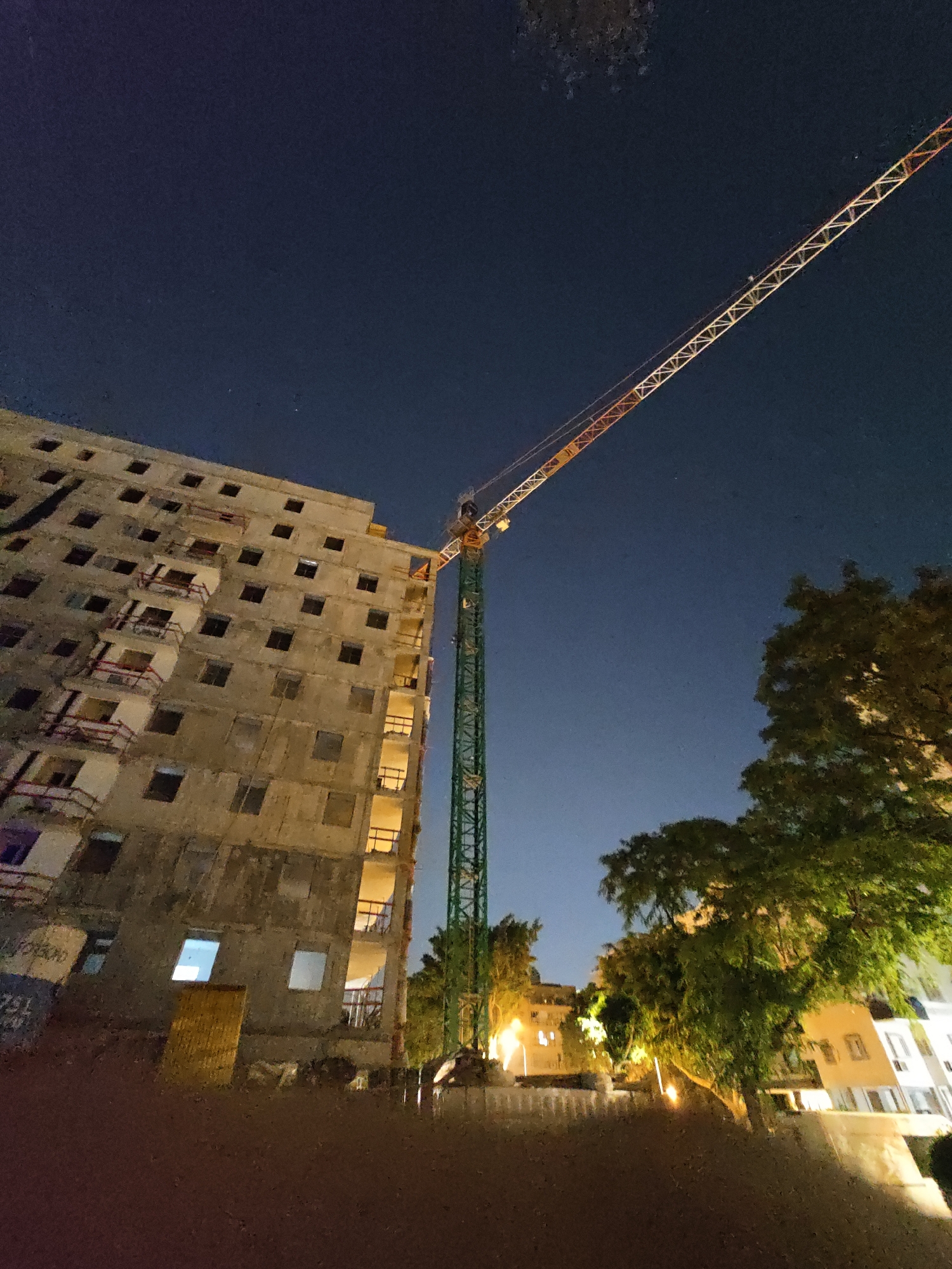 Construction crane over unfinished high-rise in Petah Tikva at night
