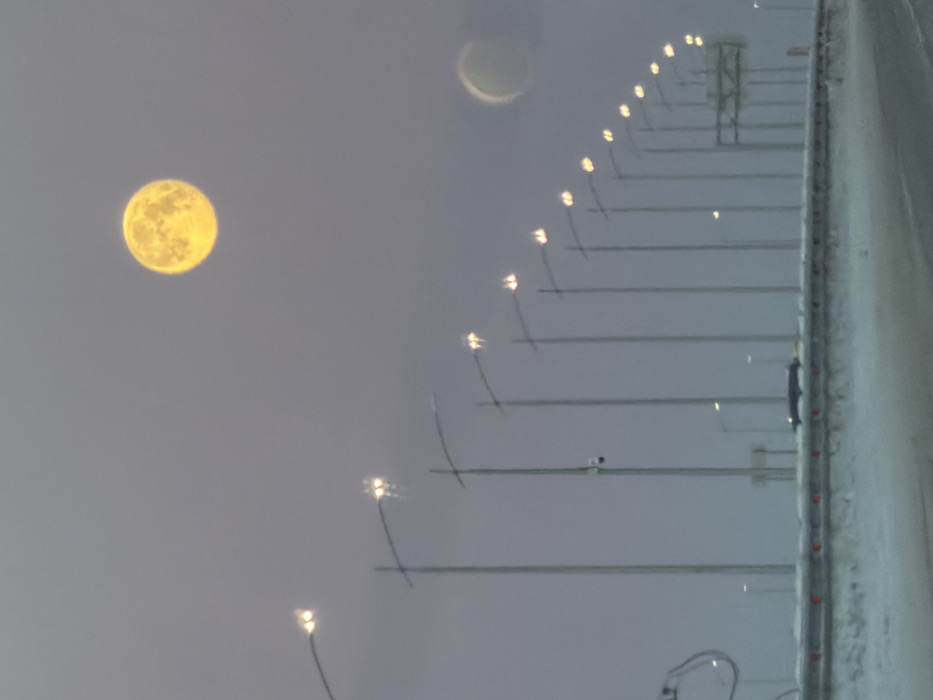 Full yellow moon observed over snowy Russian street scene