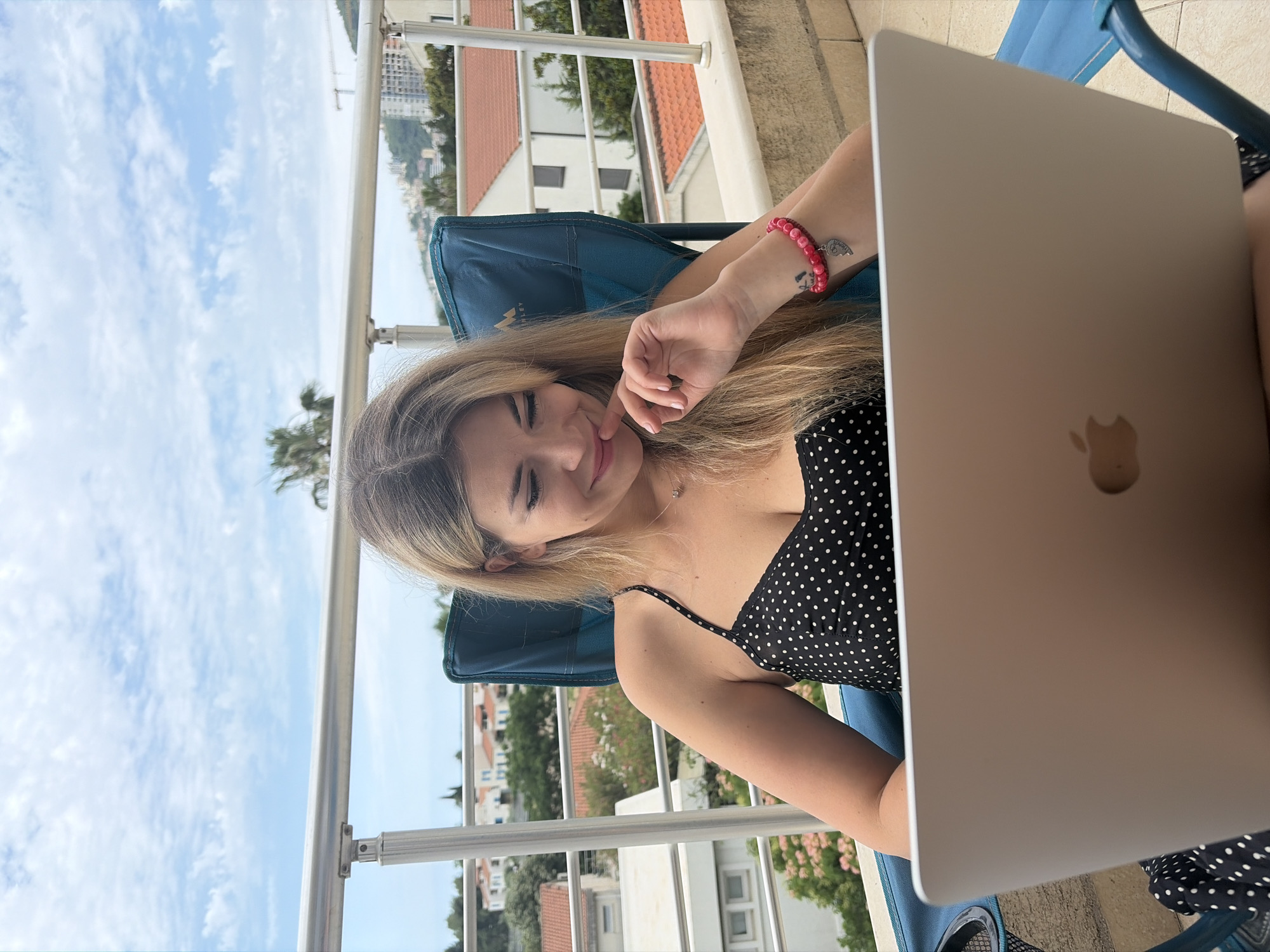 Woman works on laptop from sunny Budva balcony