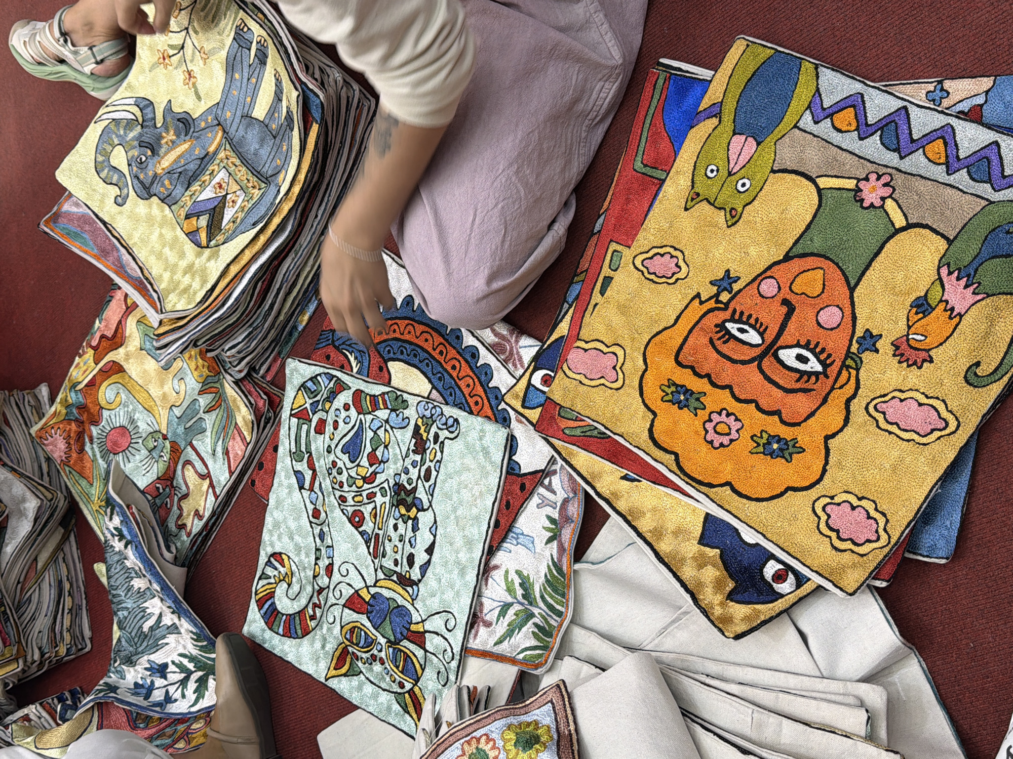 Person sits among embroidered pillows in Pokhara marketplace