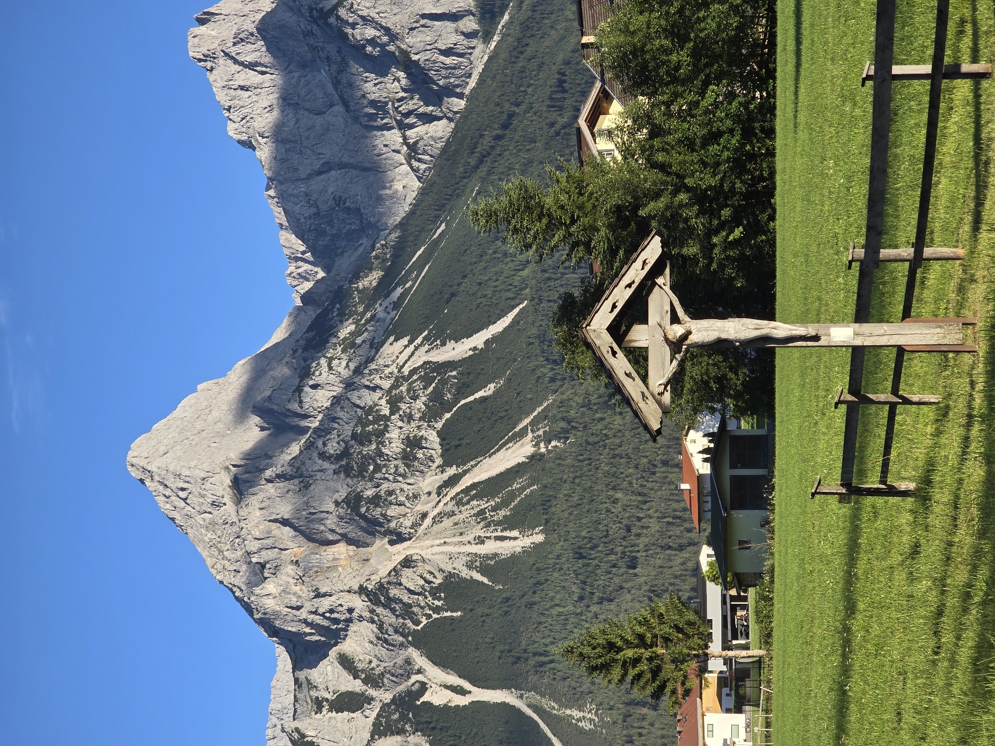 Wooden cross and alpine peaks on a clear day in Lermoos