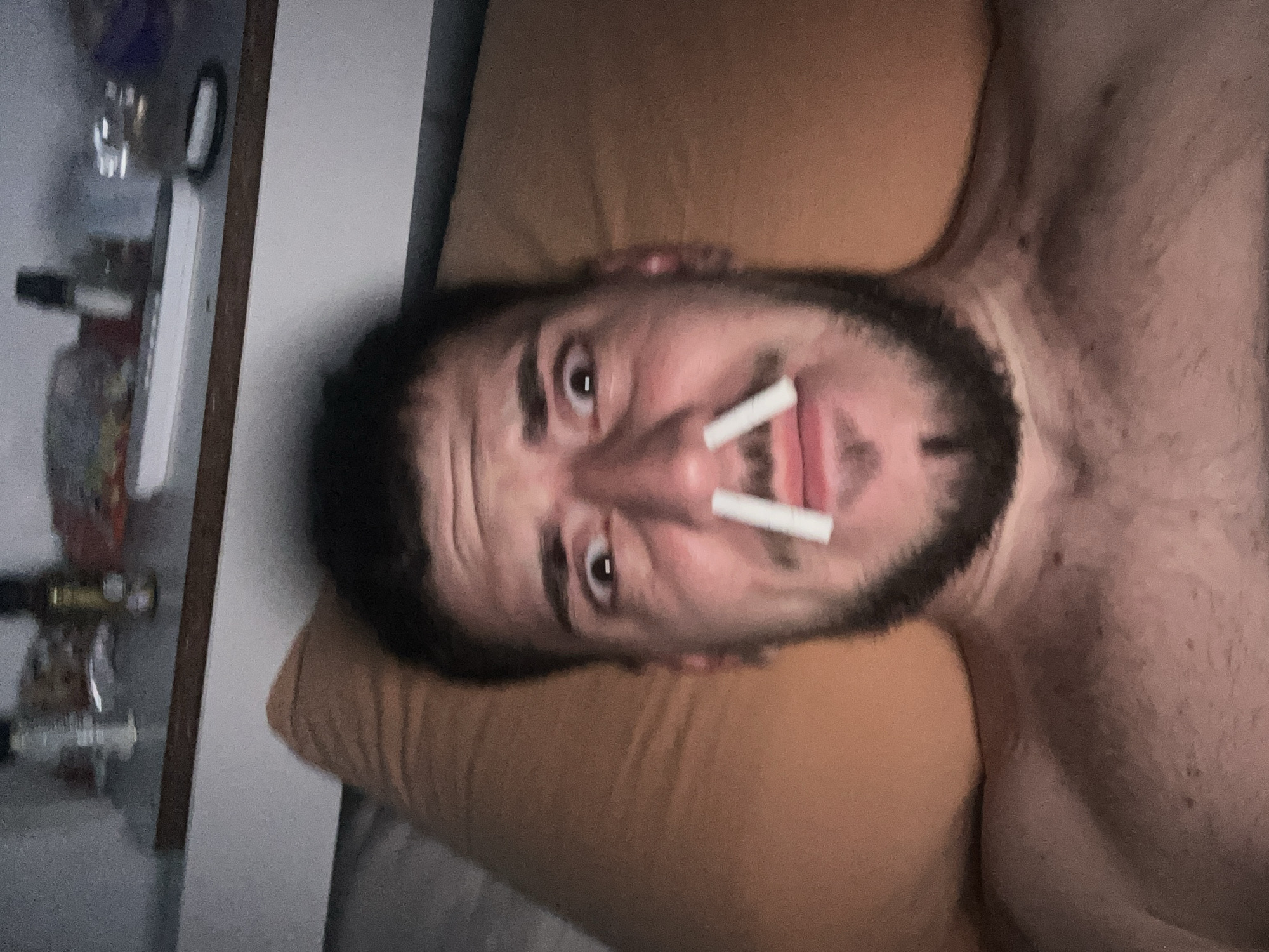 Man places cigarettes in nostrils while lying on bed