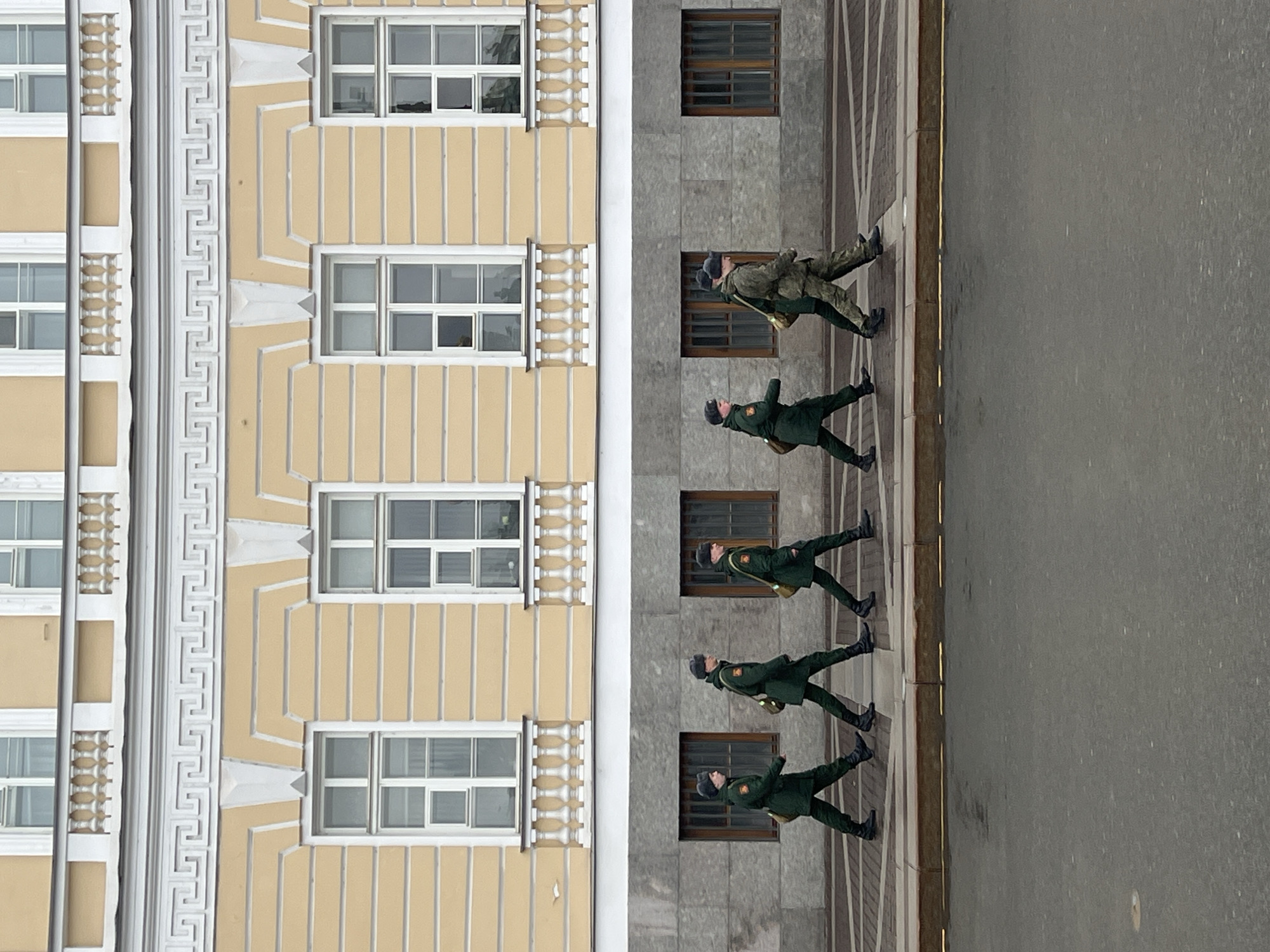 Soldiers march in formation near striped building in Saint Petersburg