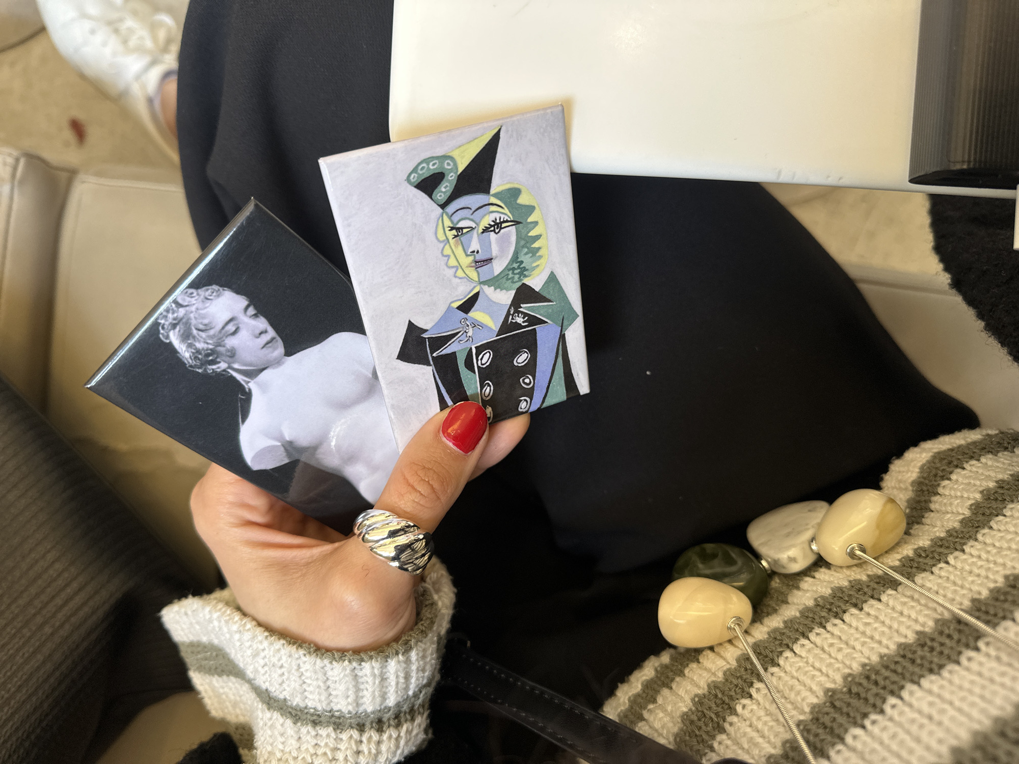 Woman examines phone and art magnets at London table