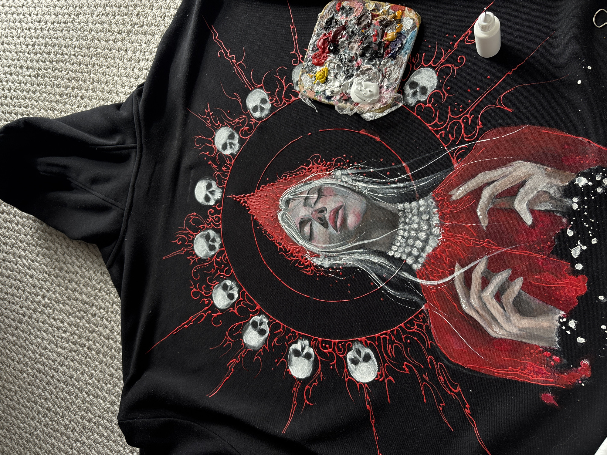 Artist hand-paints decorative designs on black garment in Krasnoyarsk