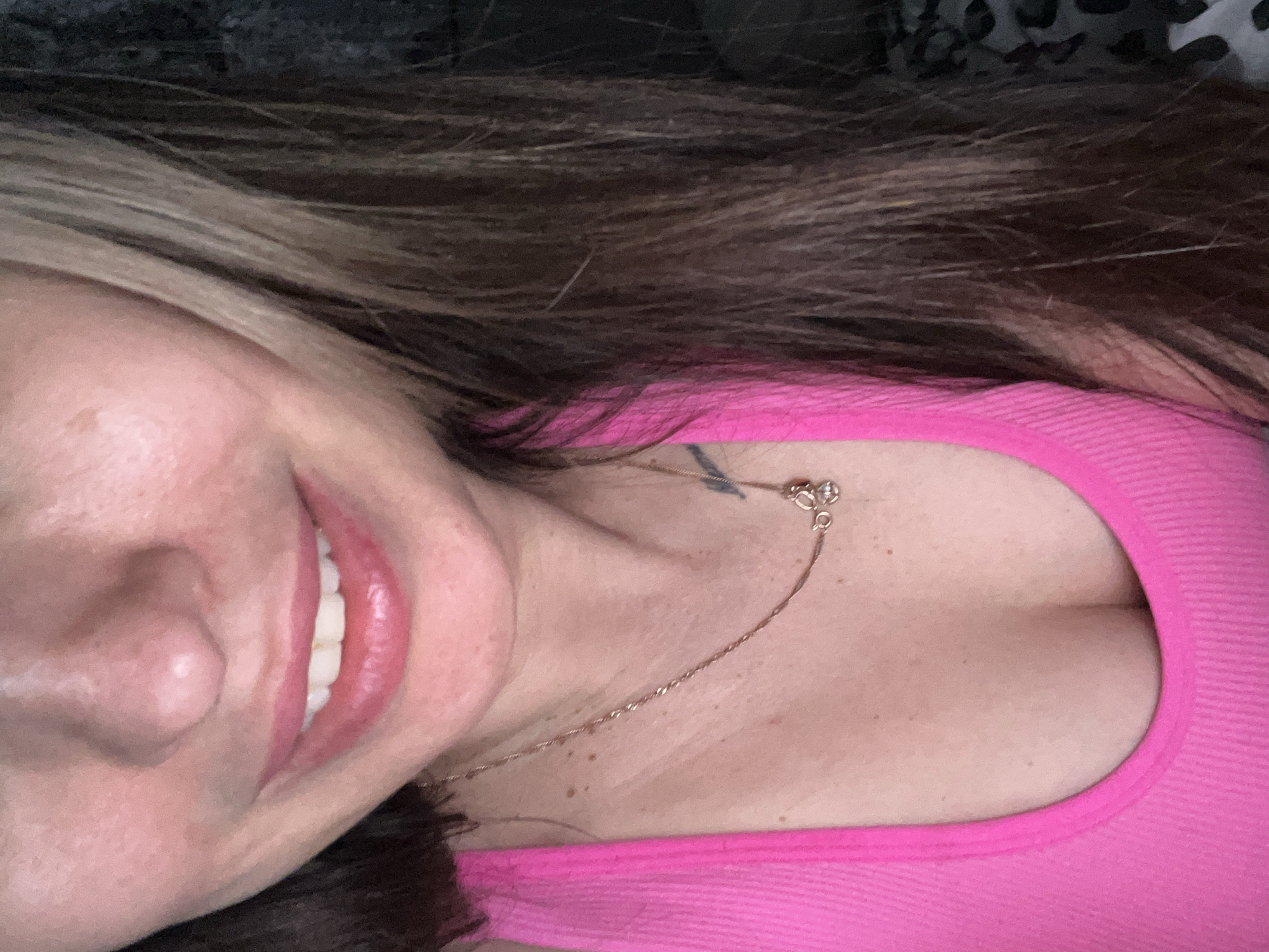 Woman takes casual selfies in pink top on patterned bedding