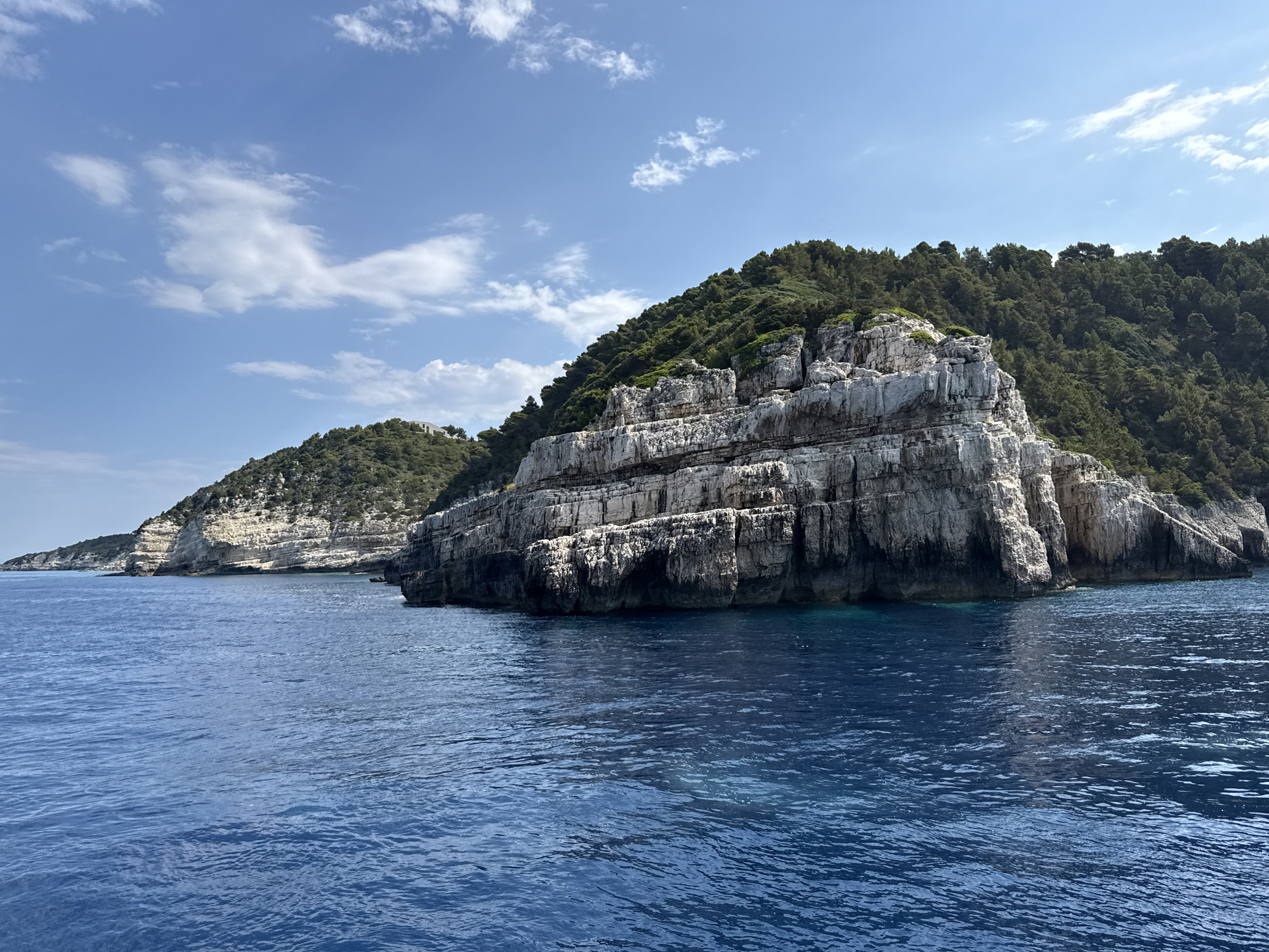 Rocky Greek coastline where green cliffs meet sapphire sea