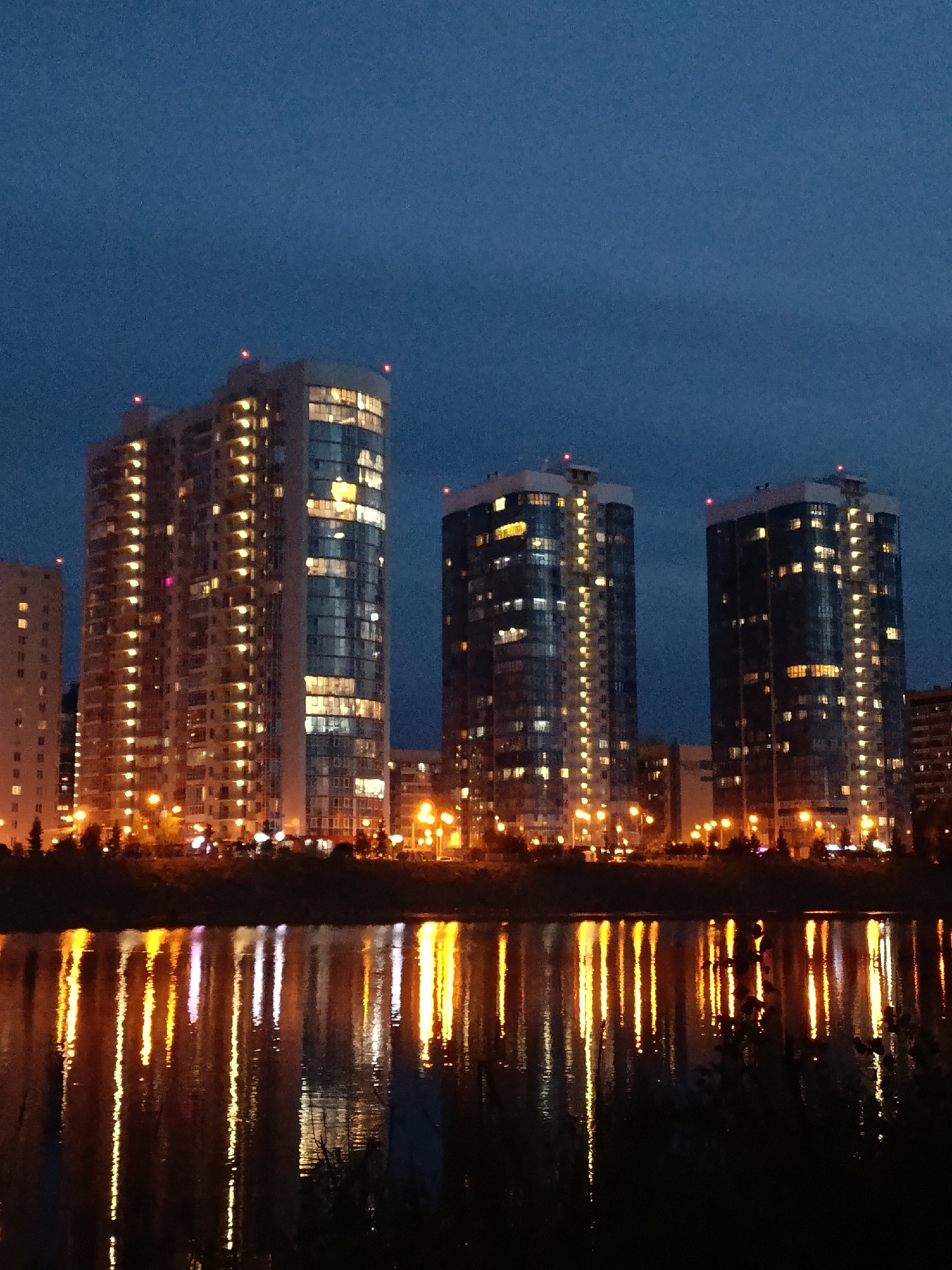 Krasnoyarsk riverfront high-rises glow at dusk along the Yenisei