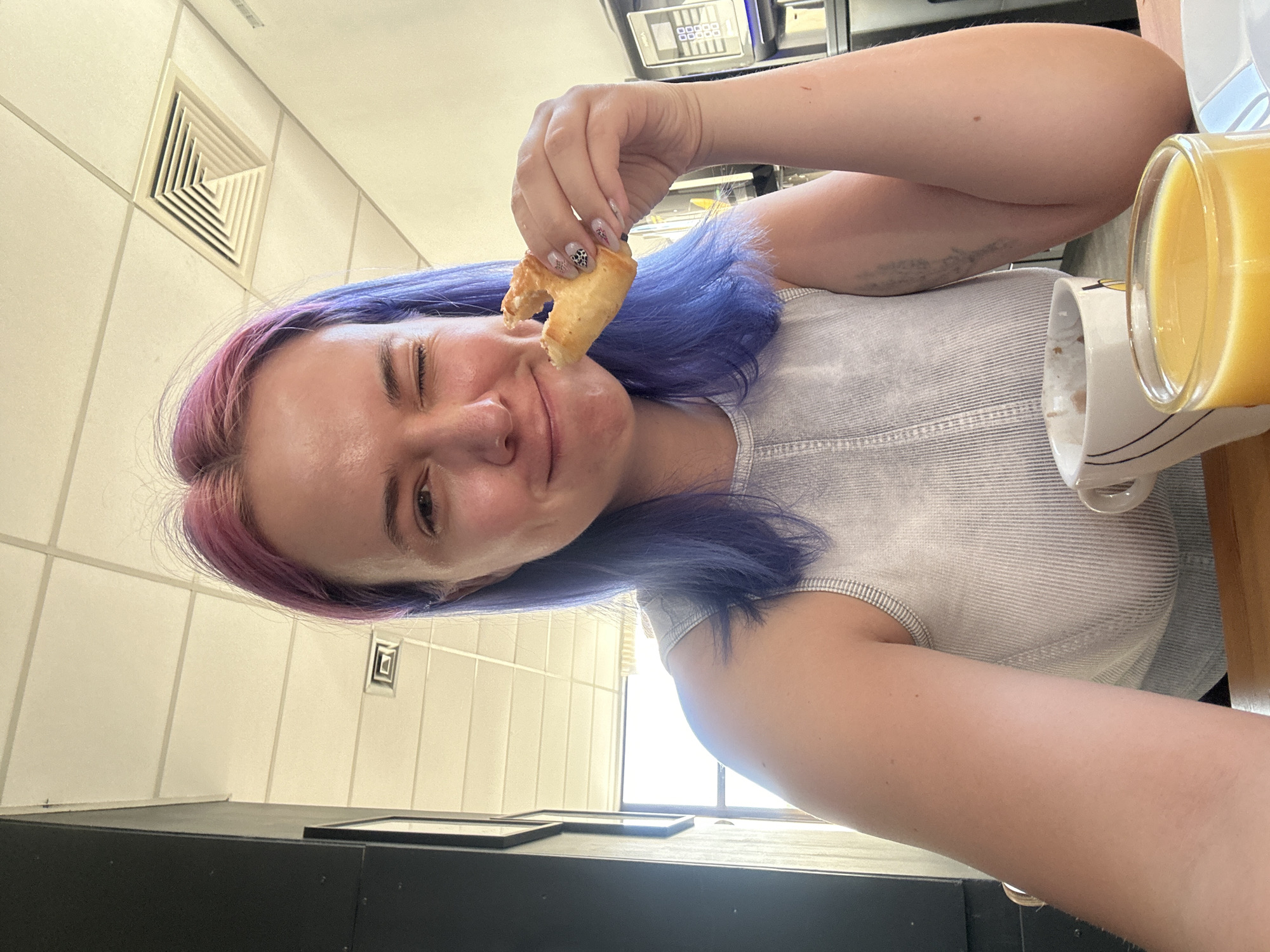 Colorful-haired woman enjoys breakfast at French cafe