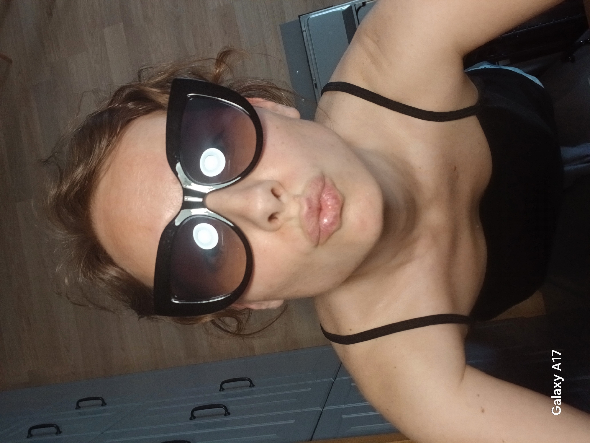 Woman documents sunglasses selfie session in Yekaterinburg apartment