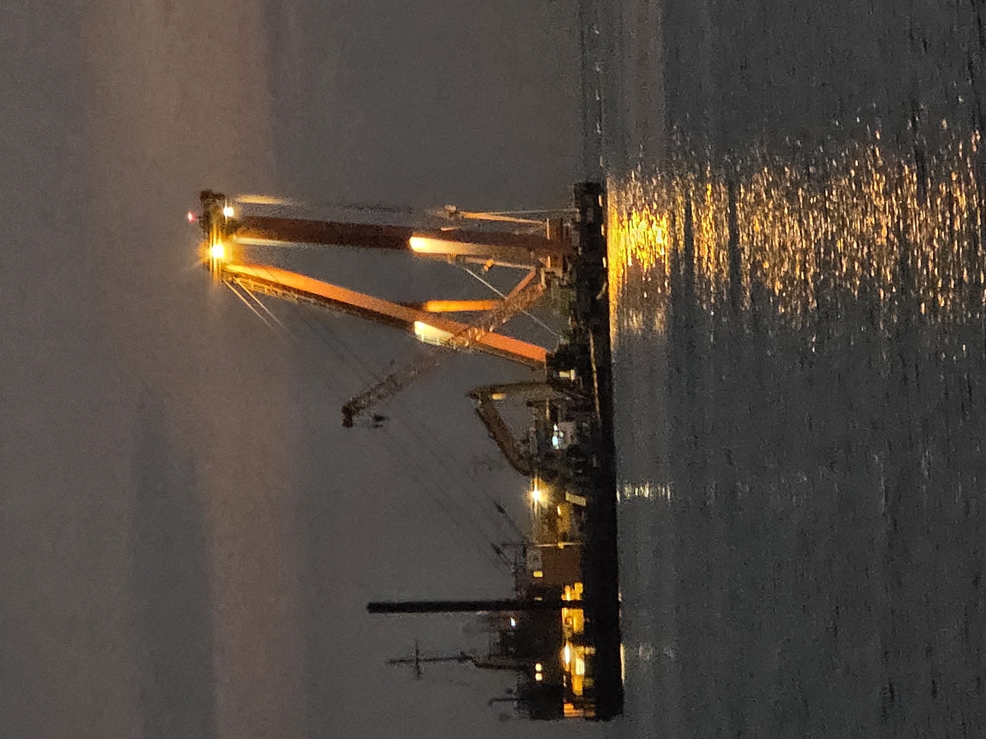 Dusk hits the Dierhagen coast alongside a lit construction barge