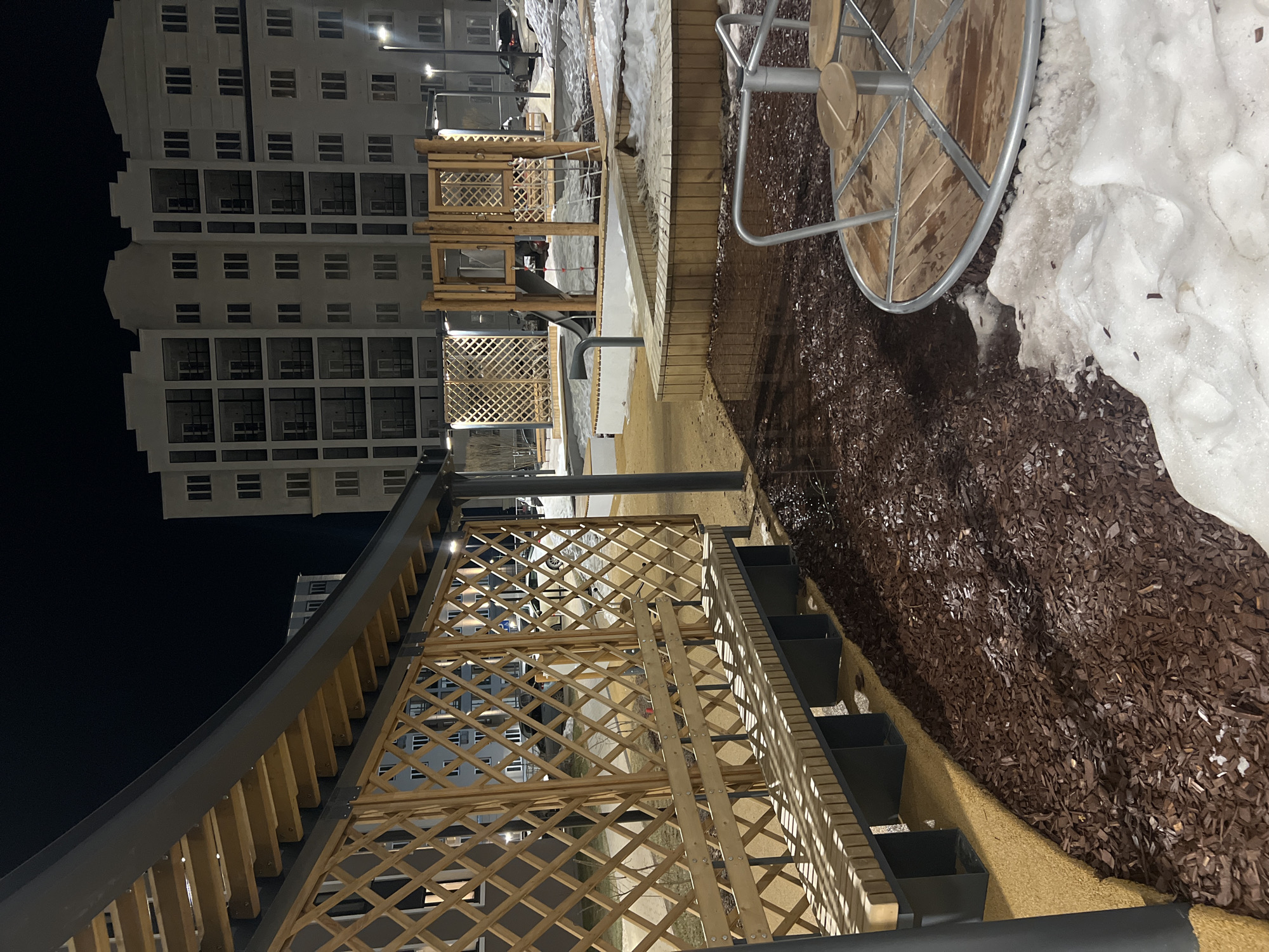 Woman relaxes on swing in snowy nighttime courtyard