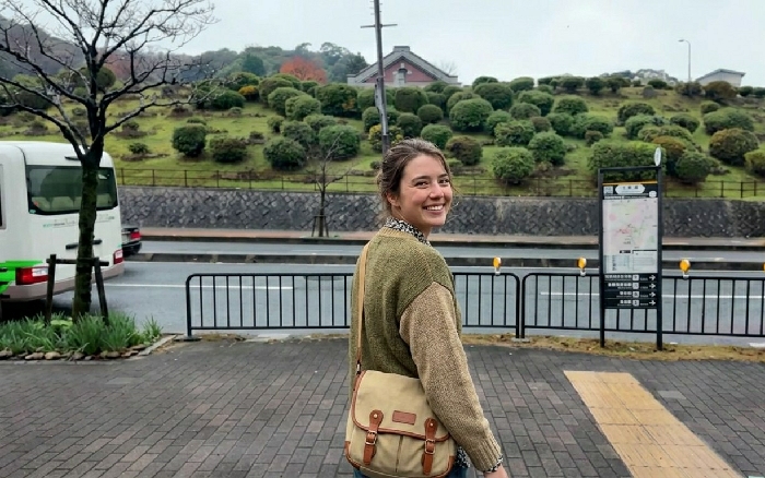 Woman photographed smiling on Kyoto sidewalk near traditional restaurant