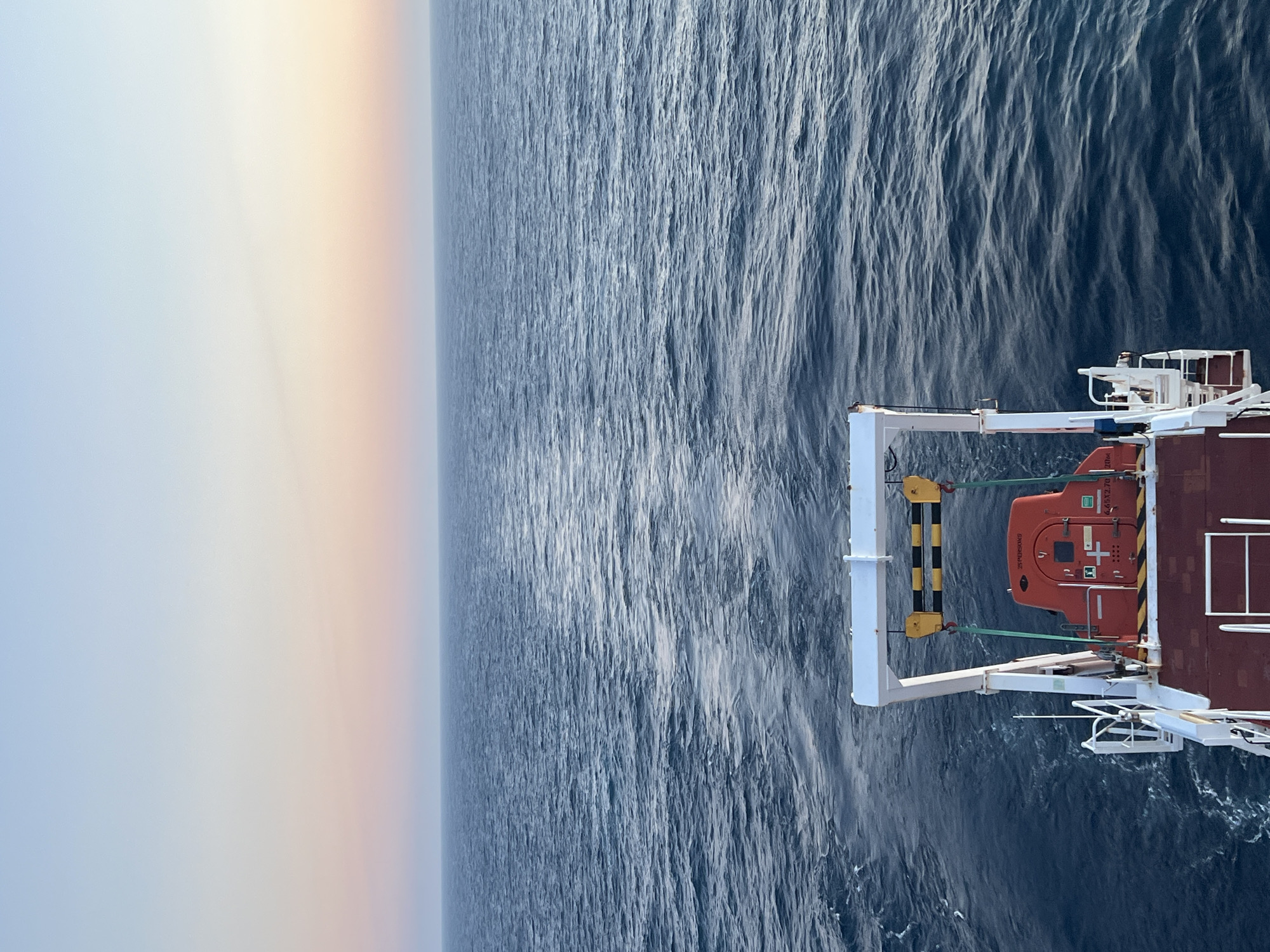 Ship at sea during golden hour, stern and aerial views