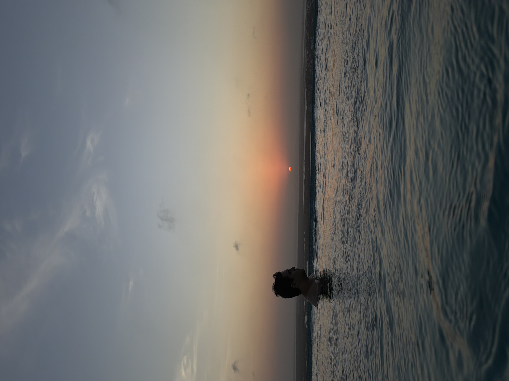 Man stands chest-deep in water during Tampico sunset