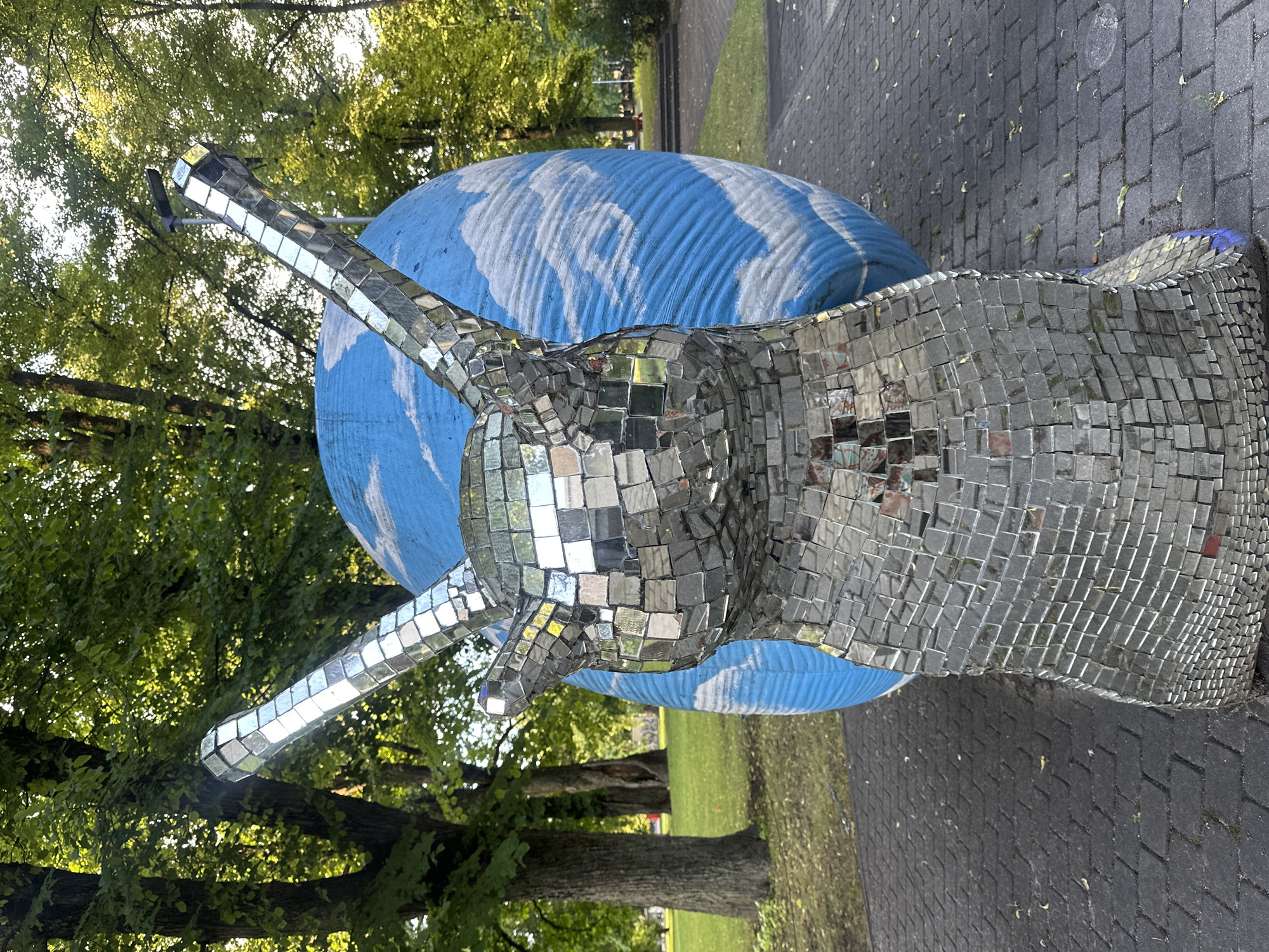 Riga park: mirrored snail sculpture and kayakers on a summer afternoon