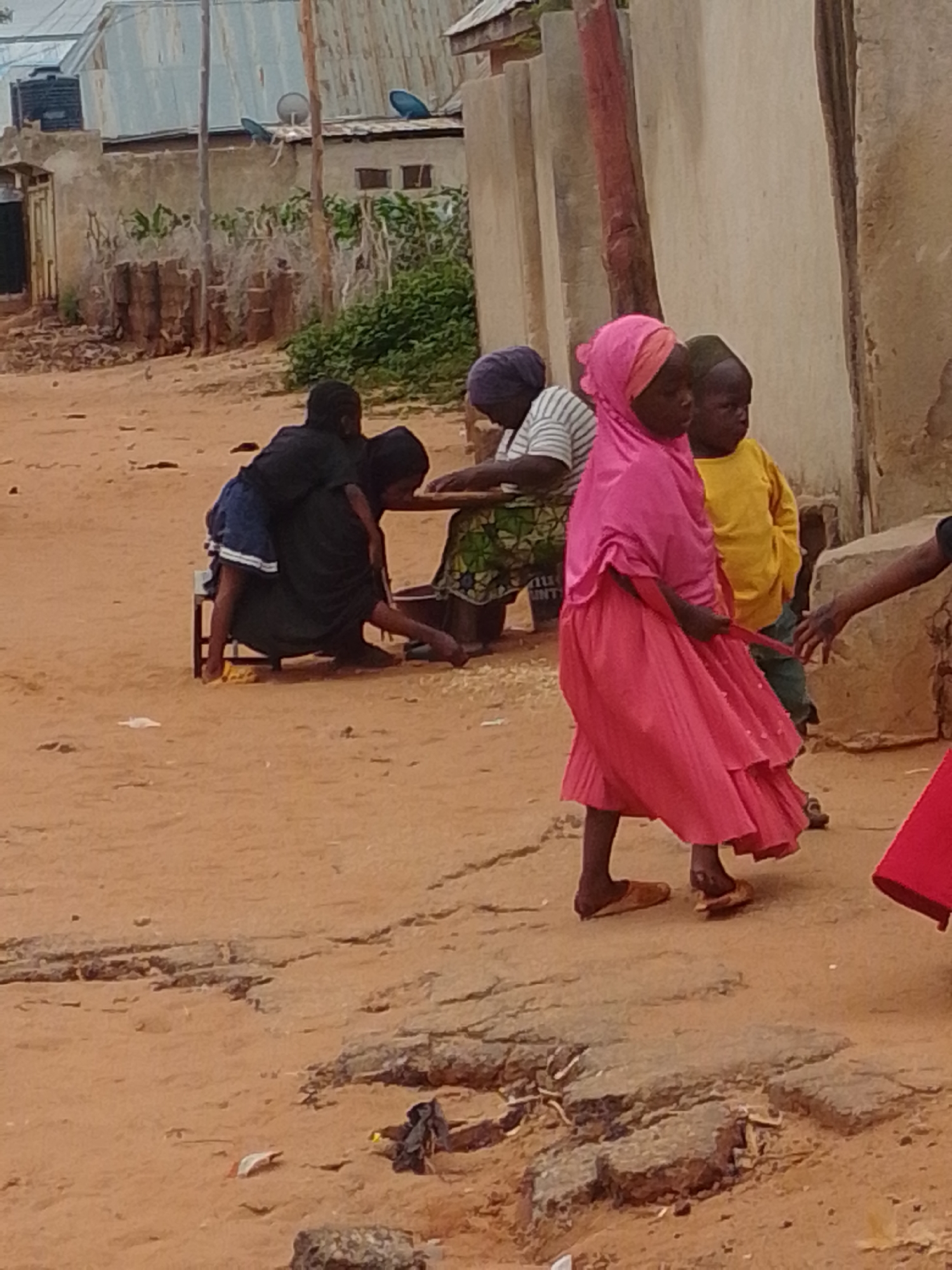 Everyday street life in a dusty, unidentified residential neighborhood.