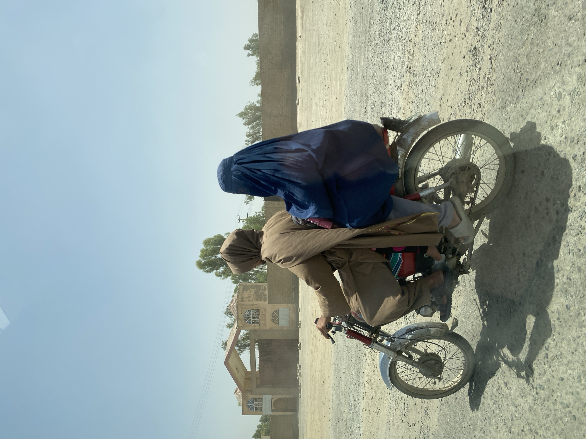 Routine stop at a Kandahar gas station, motorcycle passing nearby