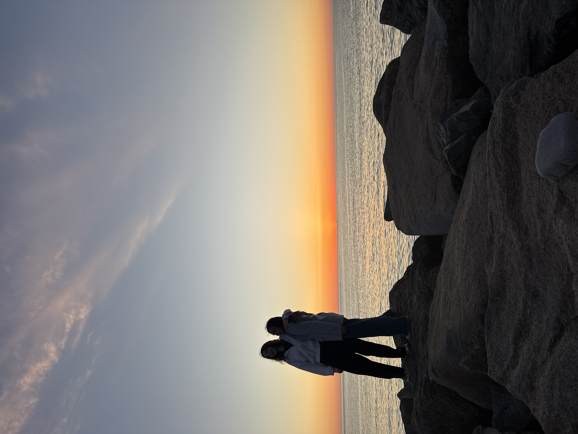 Two women stand on coastal rocks in Batumi
