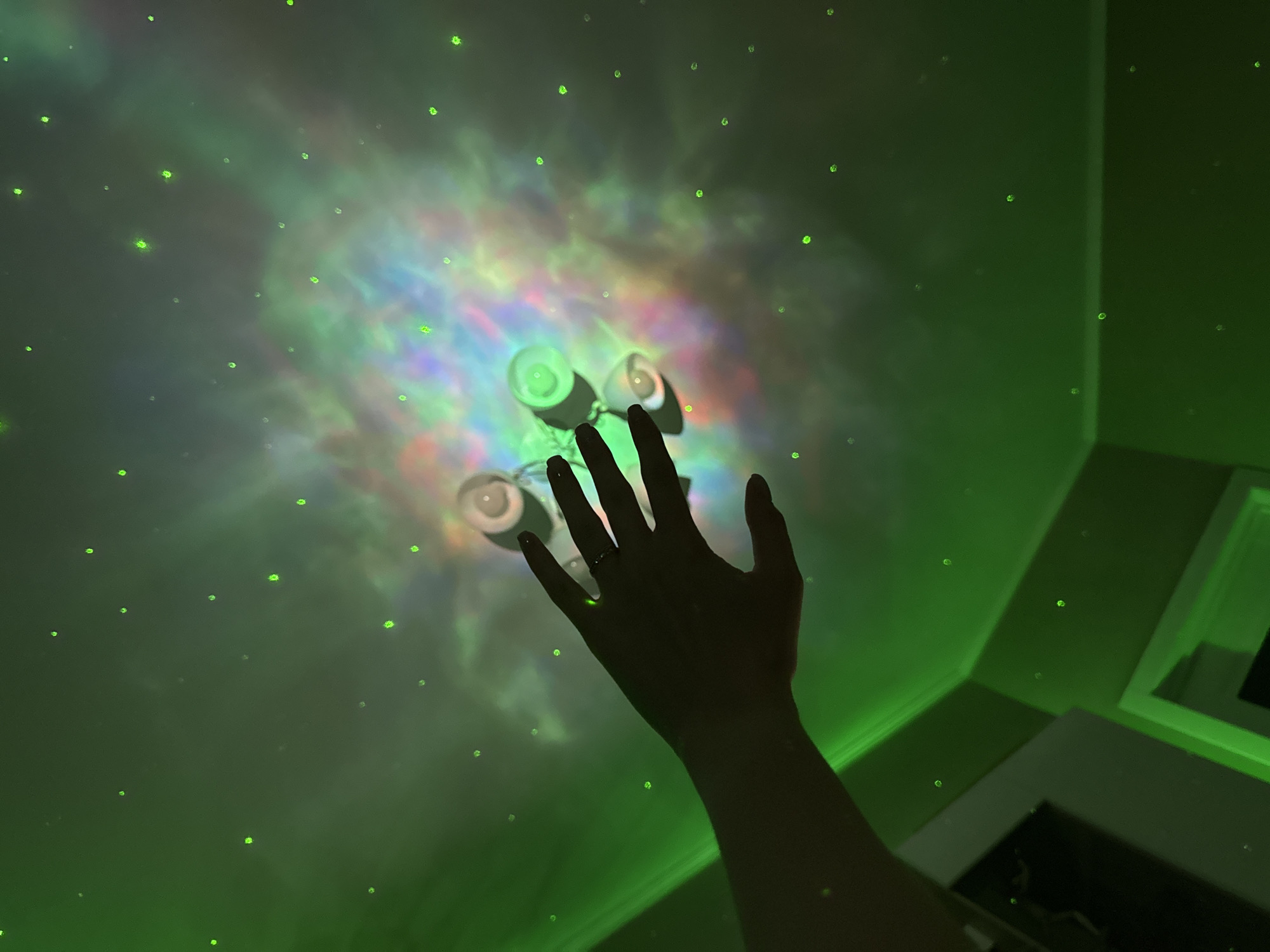 Galaxy projector and mood lighting fill a decorated bedroom.