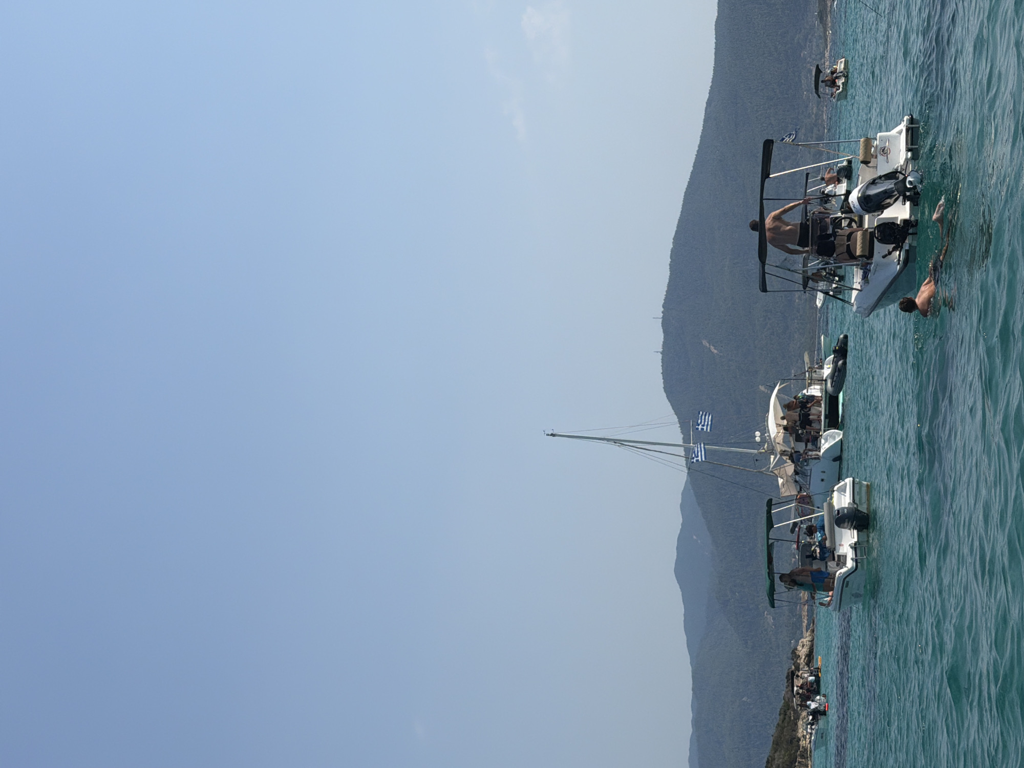 Boats anchored in calm turquoise waters off the Greek coast