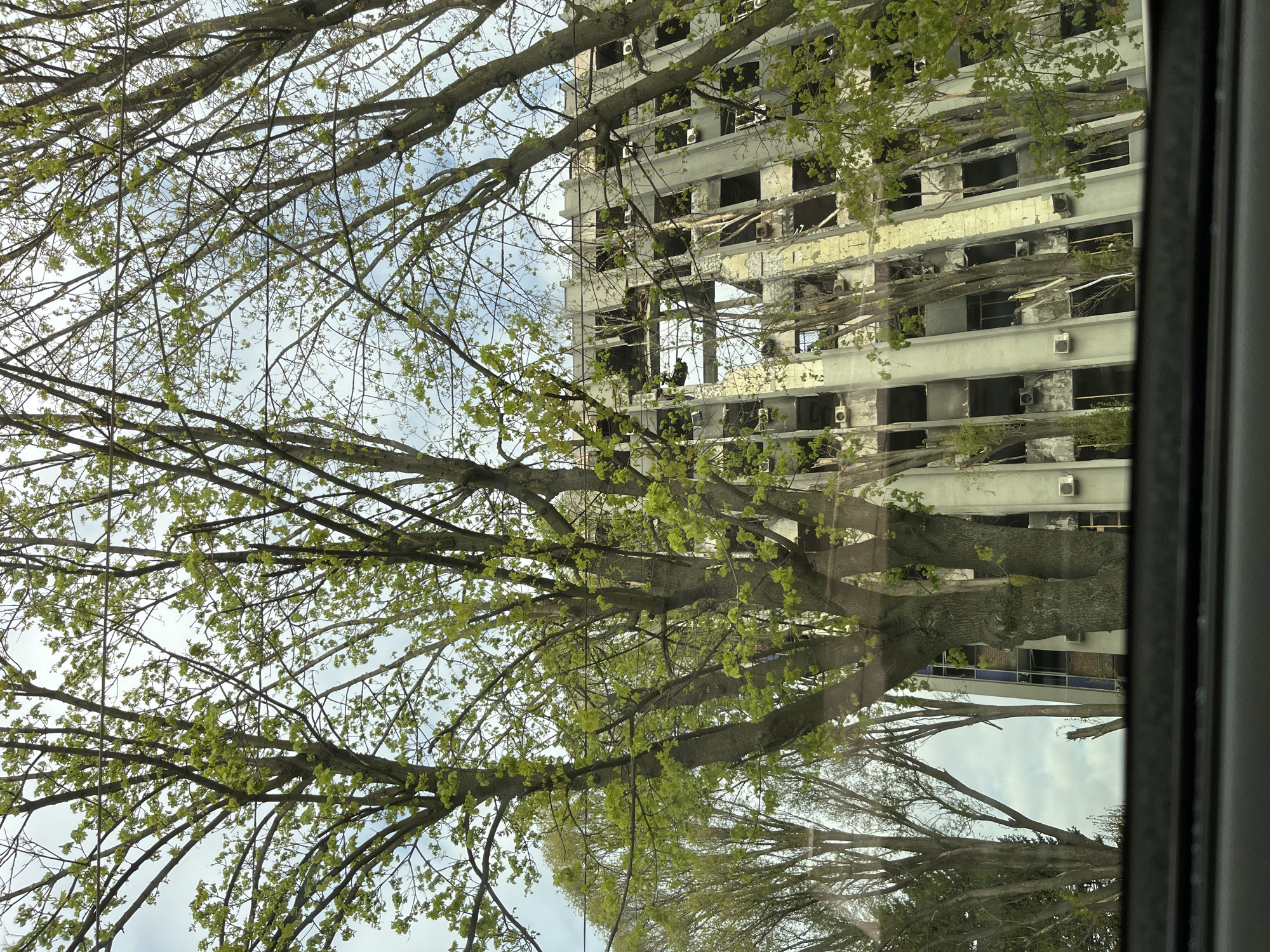 Damaged building observed through spring foliage in Dnipro, Ukraine