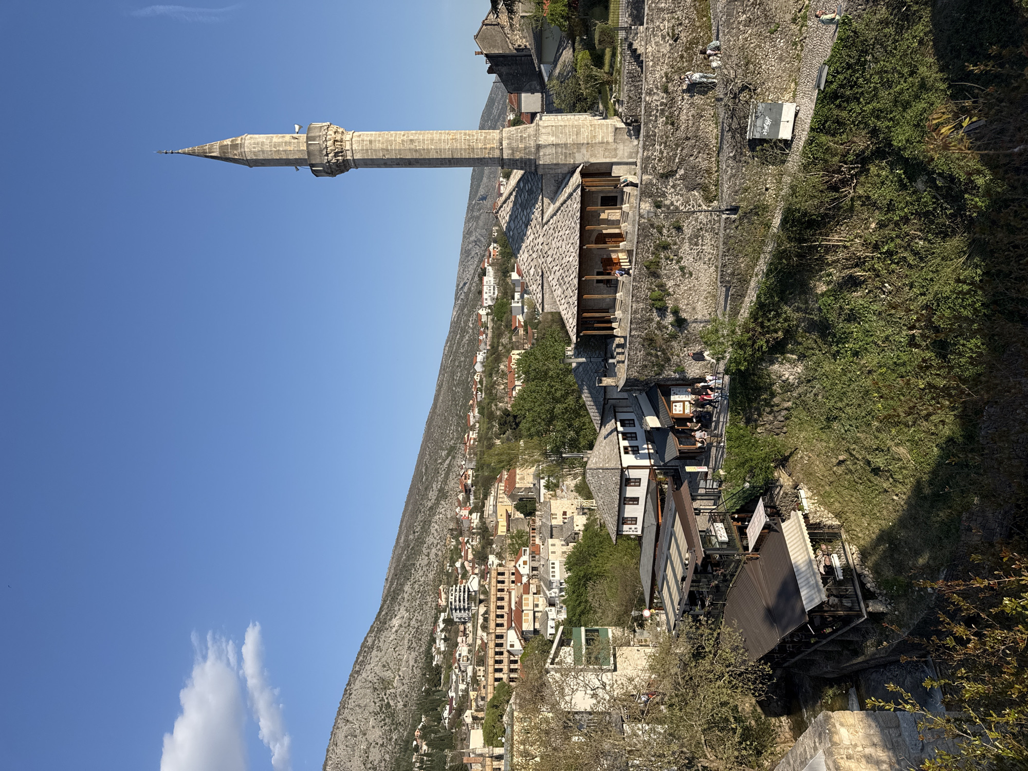 Stone minaret stands tall against blue skies in Mostar