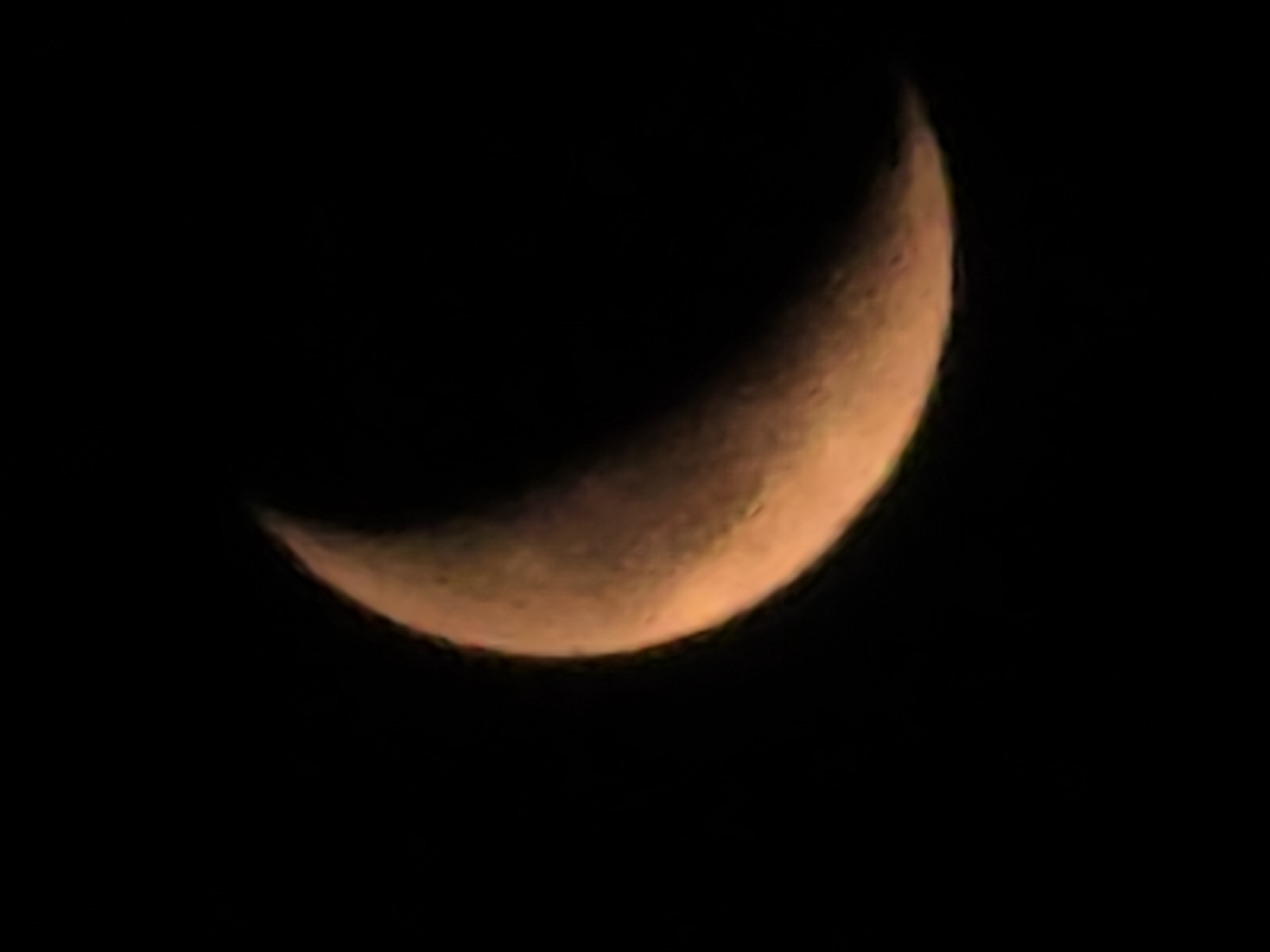 Crescent moon reflects across dark water on a quiet night