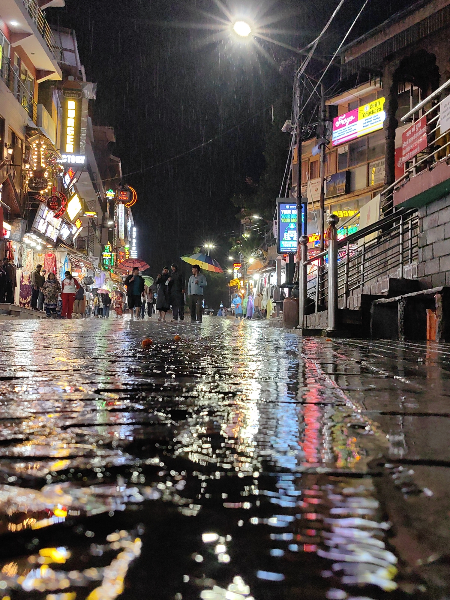 Rainy night on Mall Road, Manali — neon reflections and umbrellas