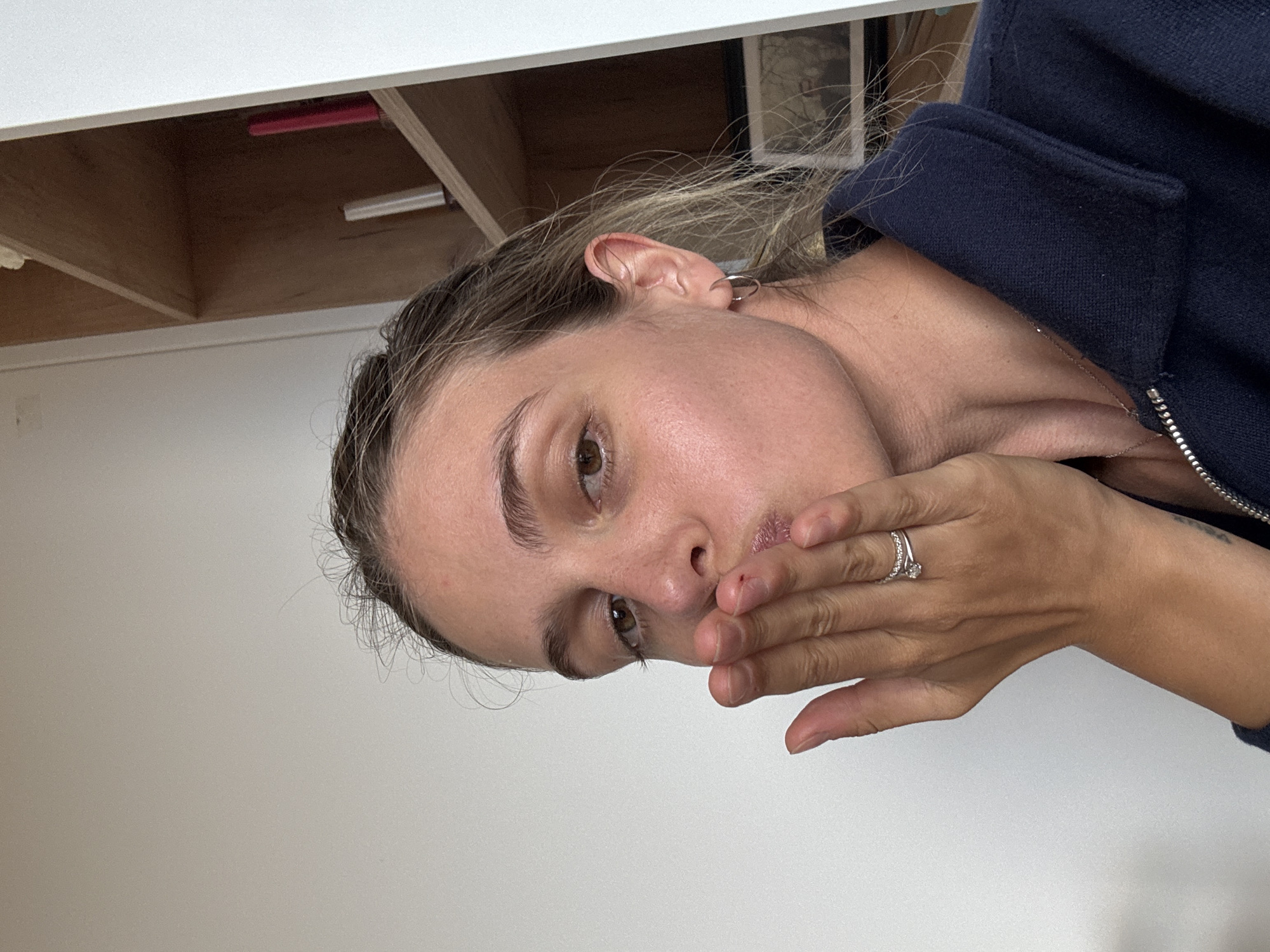 Woman covers mouth in indoor photograph
