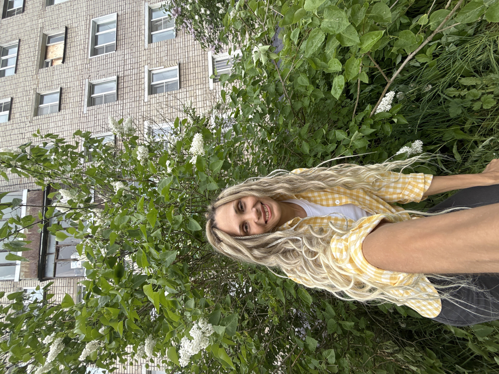 Woman poses among lilac flowers in Russian village morning