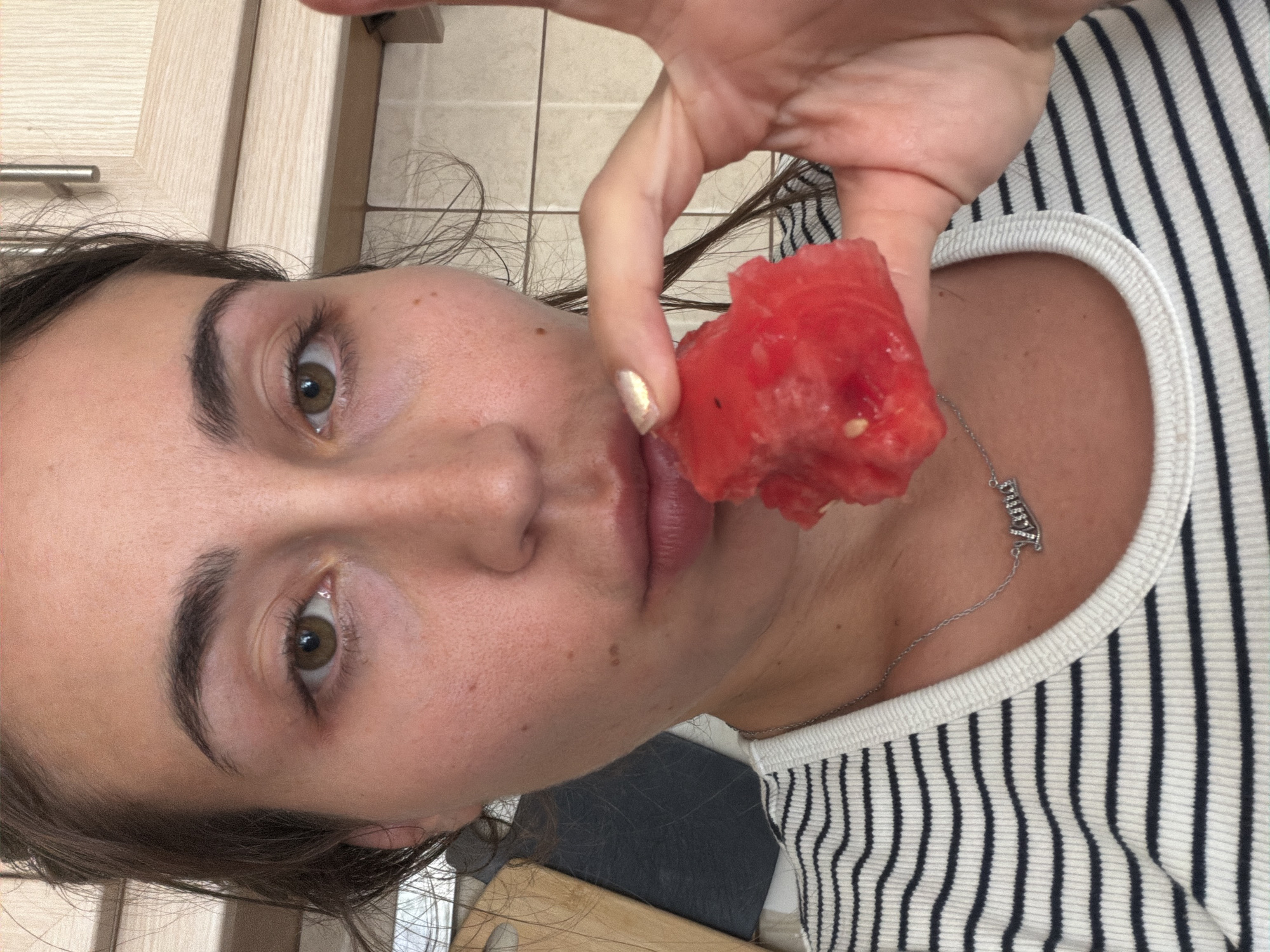 Woman enjoys watermelon snack in Tersefanou kitchen