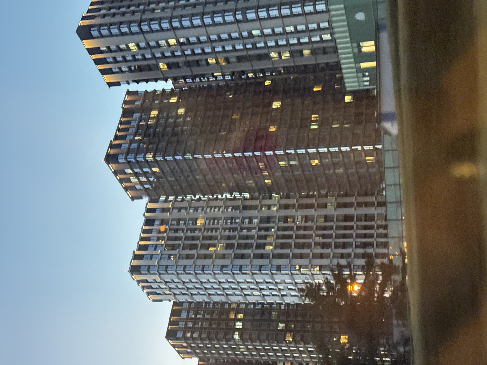 City high-rises tower overhead as lights flicker on at dusk