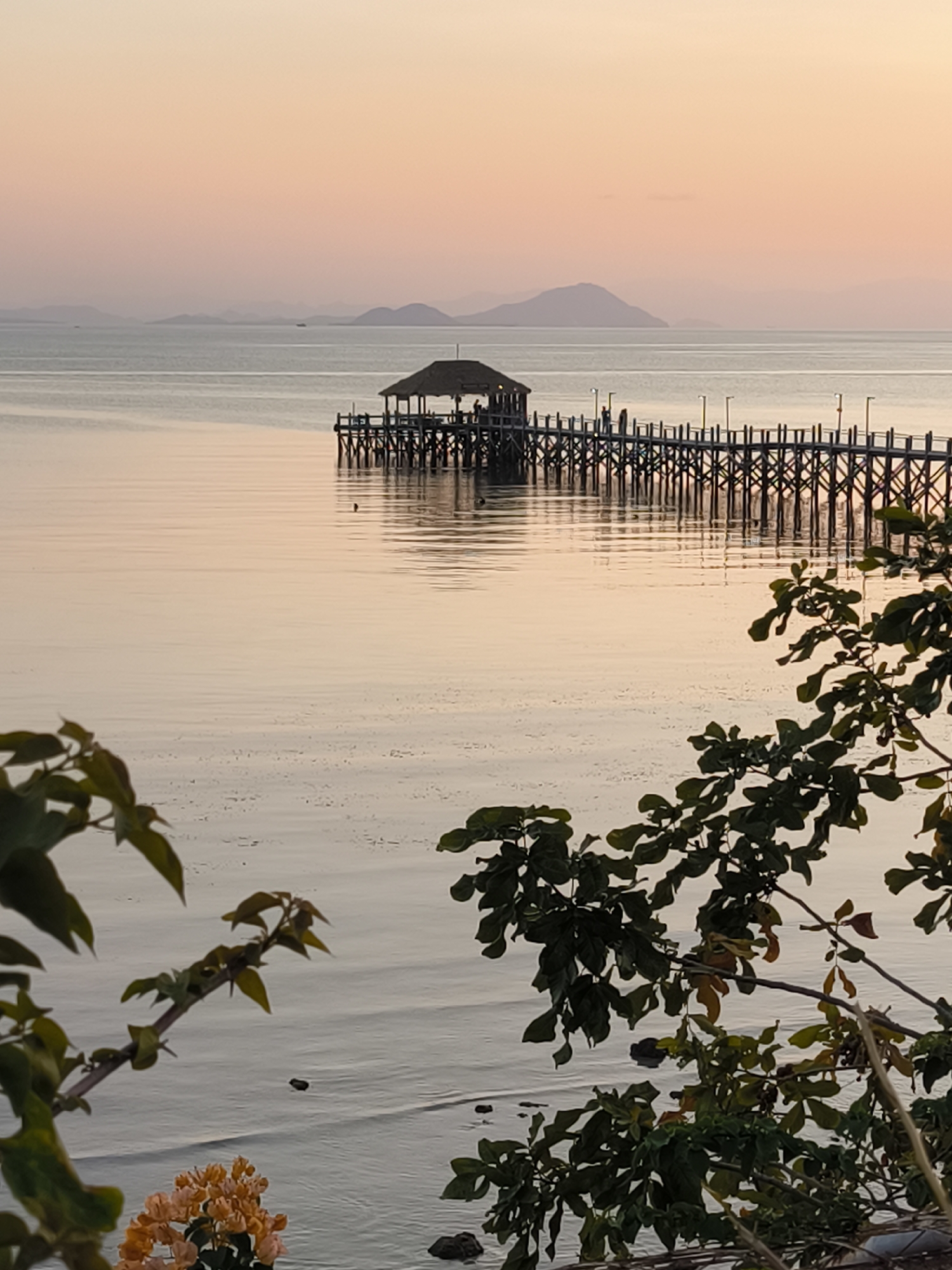 Labuan Bajo waterfront at golden hour — piers, cannons, and bougainvillea