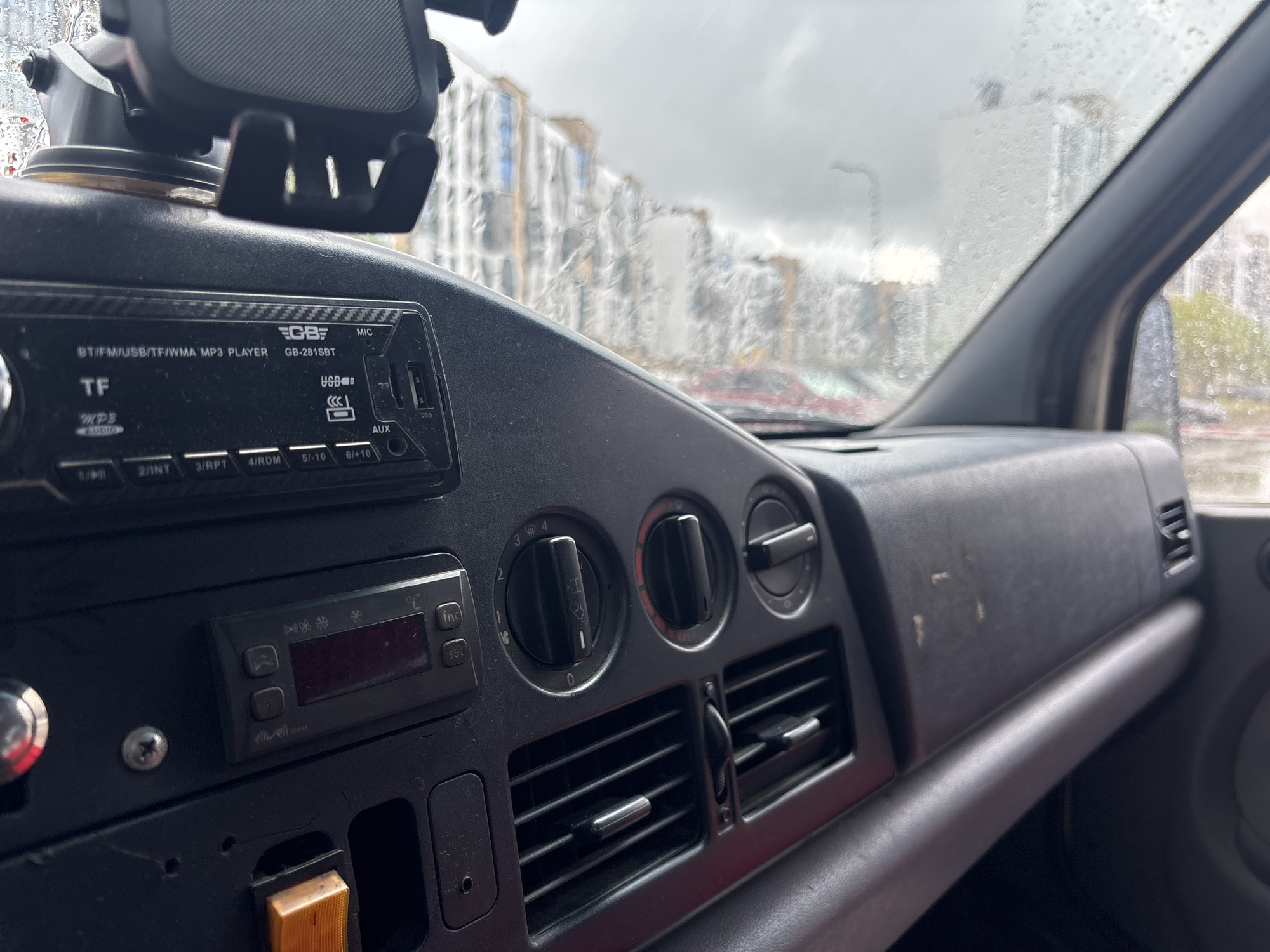 Rainy city drive past modern buildings and a parked delivery van