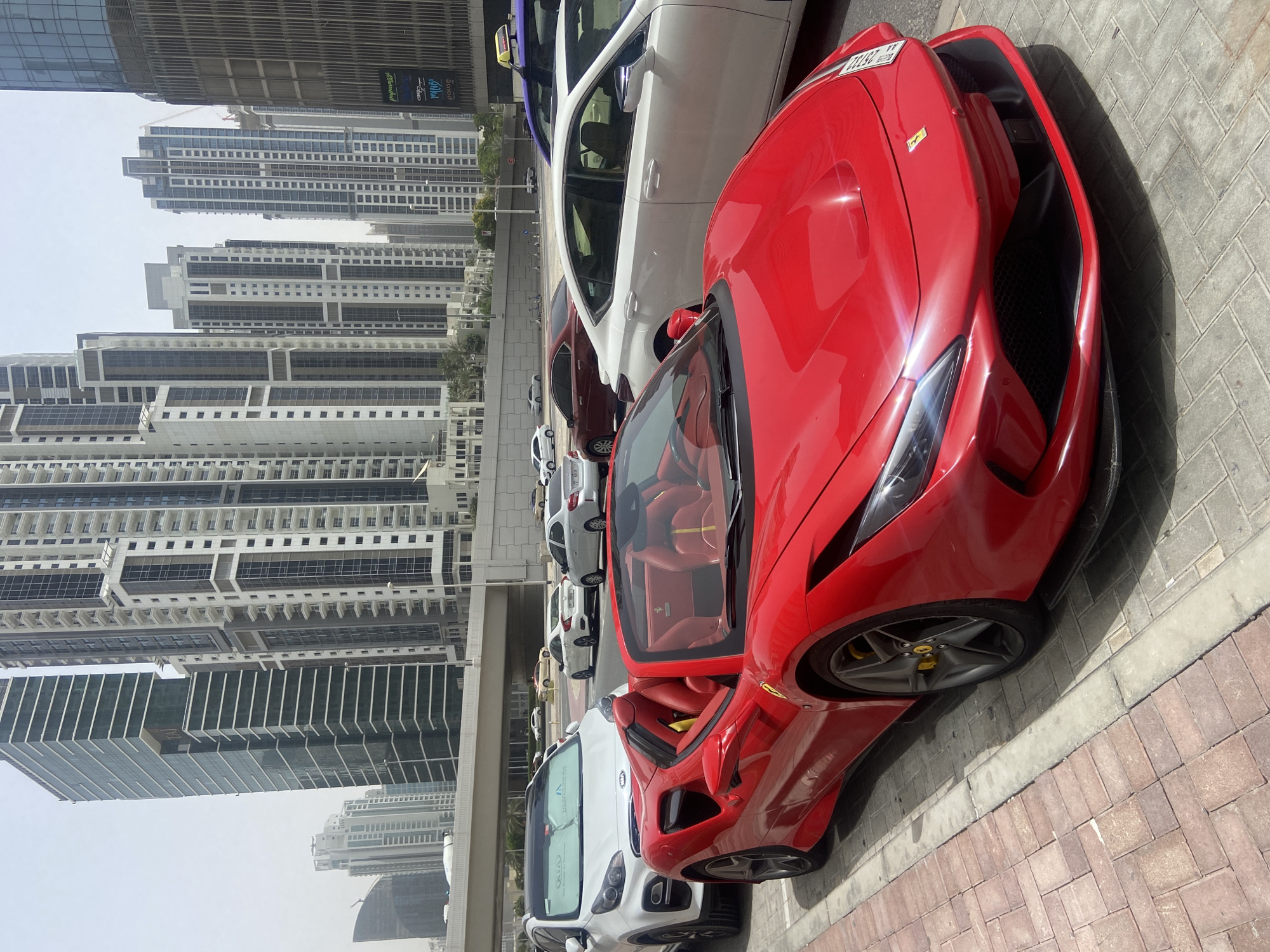 Red Ferrari spotted among parked cars in Dubai Business Bay