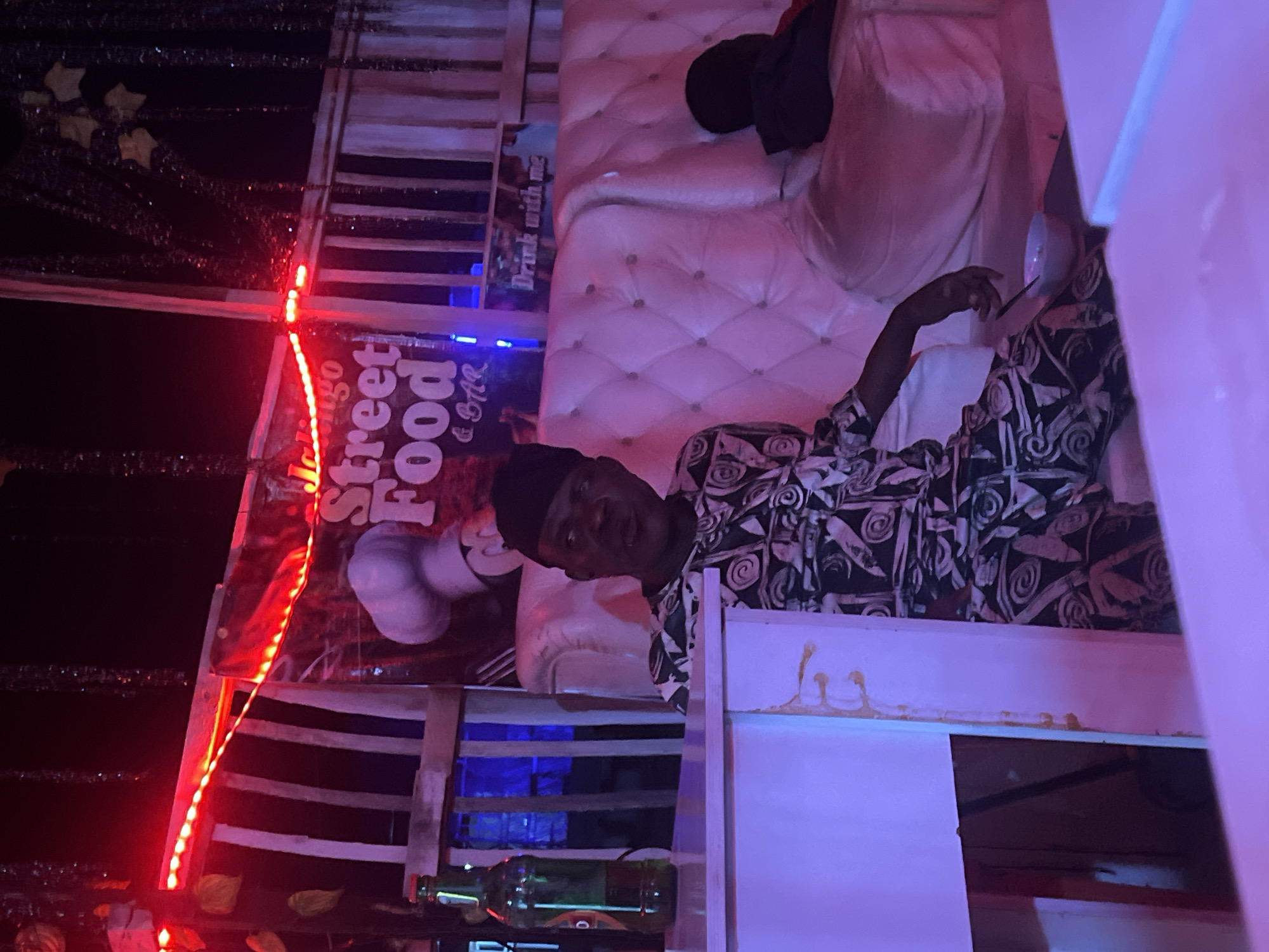 Late-night street food spot glowing under red LEDs in Nigeria