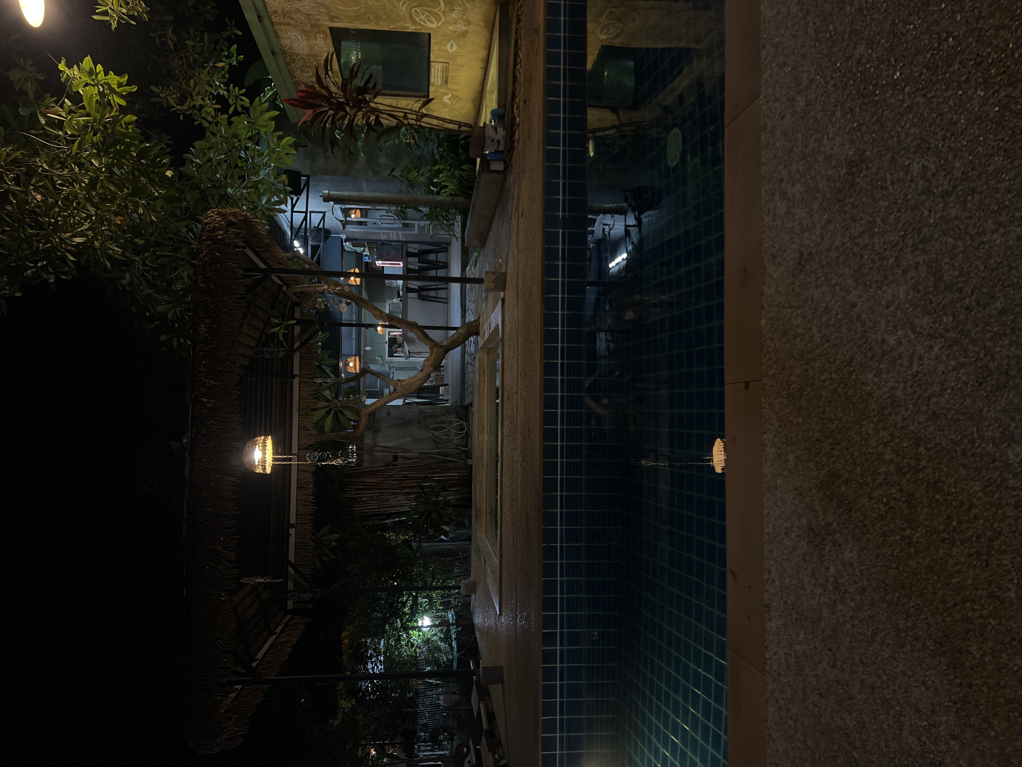 Relaxed nighttime hangout at a poolside thatched-roof retreat