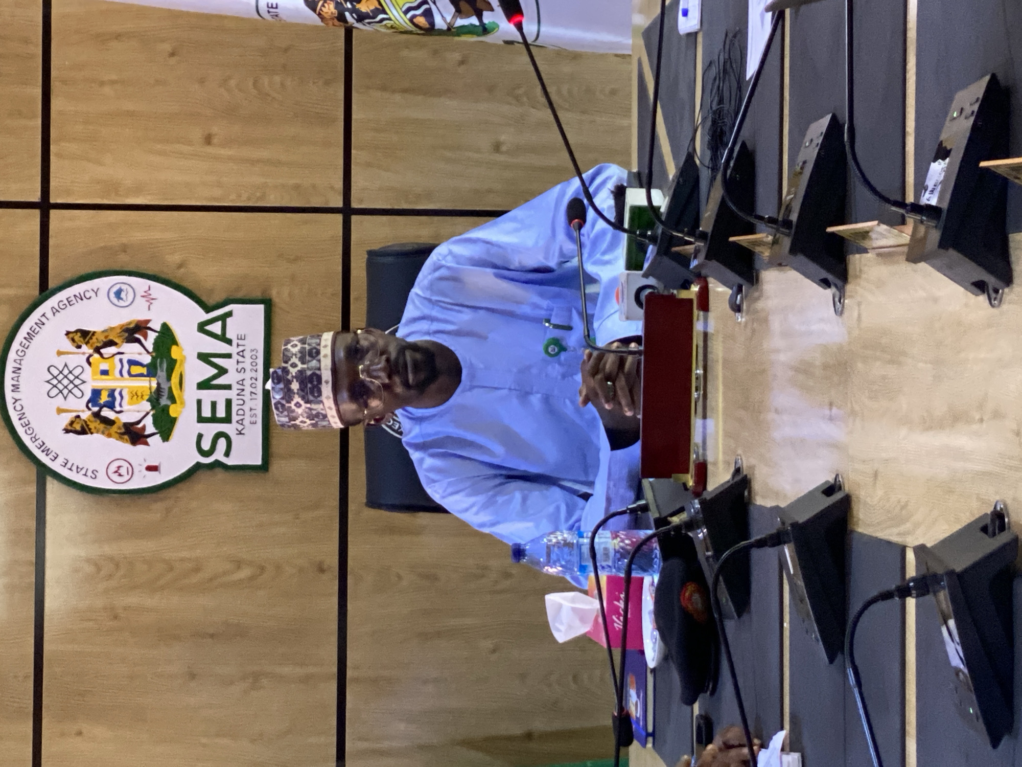 Man in traditional attire observed at indoor meeting