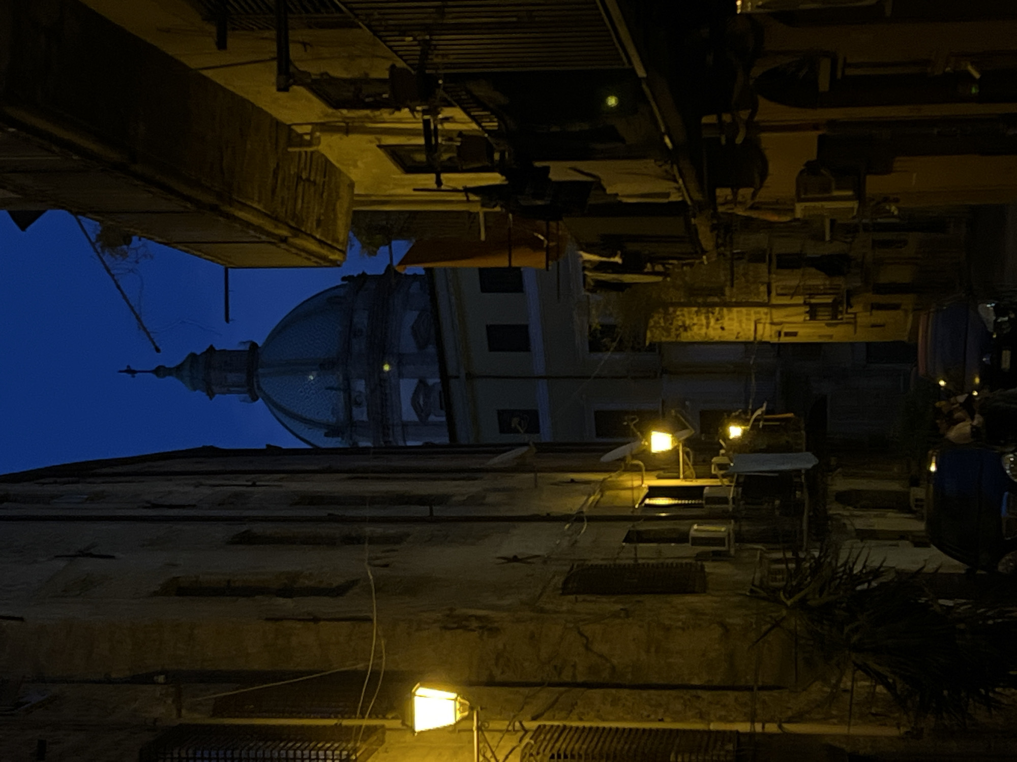Domed church silhouette over a narrow Palermo street at dusk