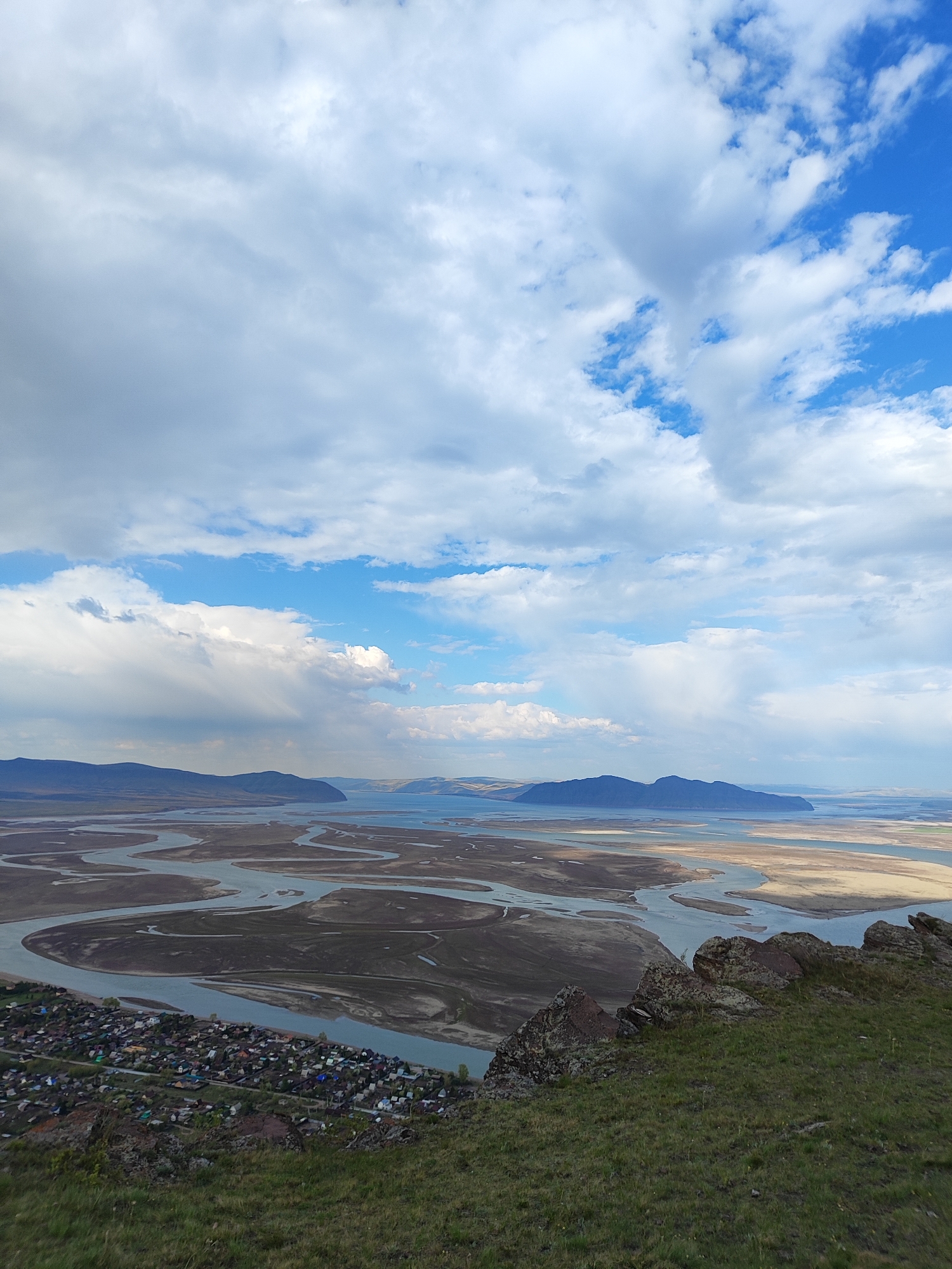 Man photographs river delta landscape from hilltop vantage point