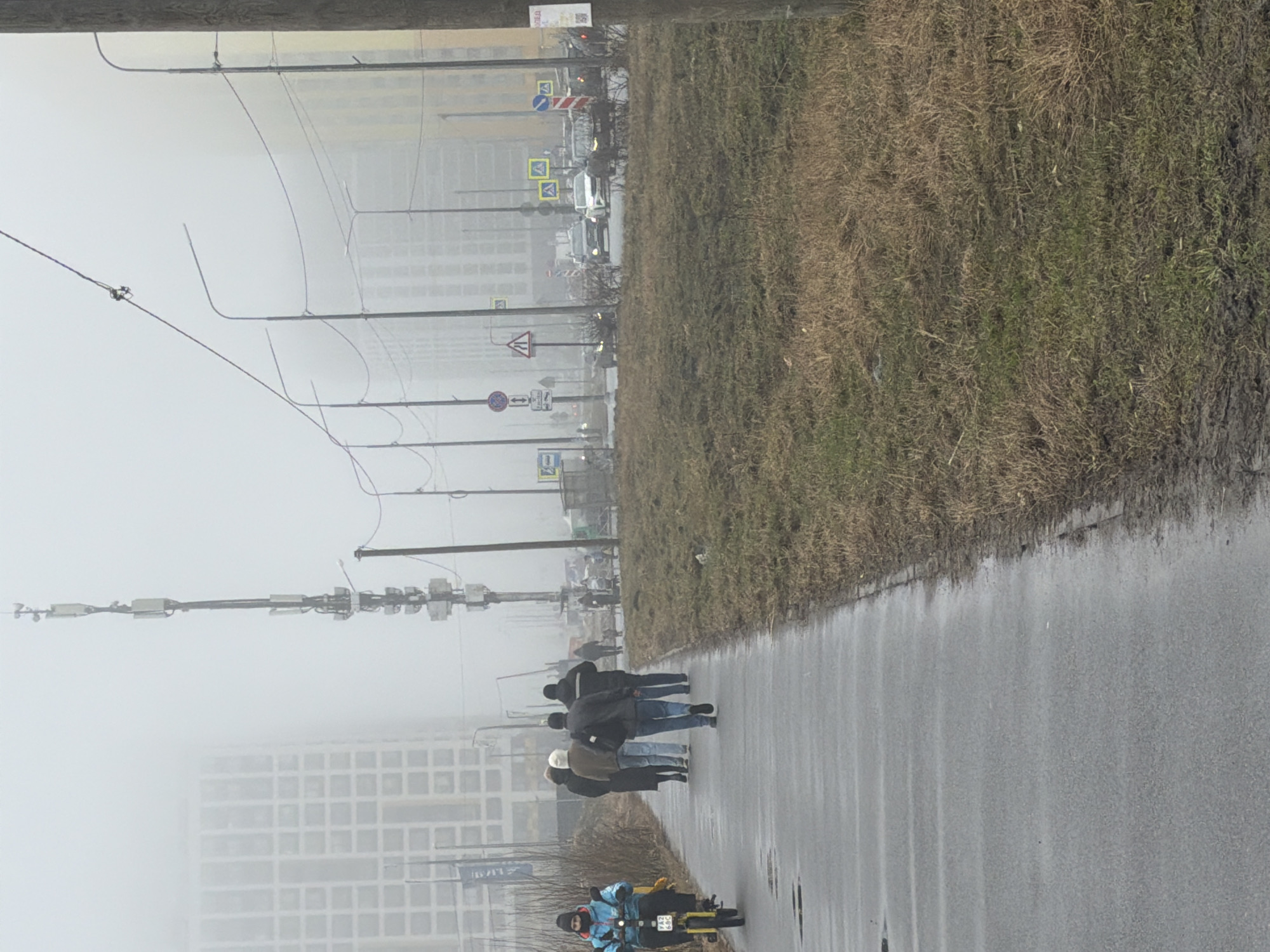 Pedestrians navigate foggy conditions on wet Murino sidewalk