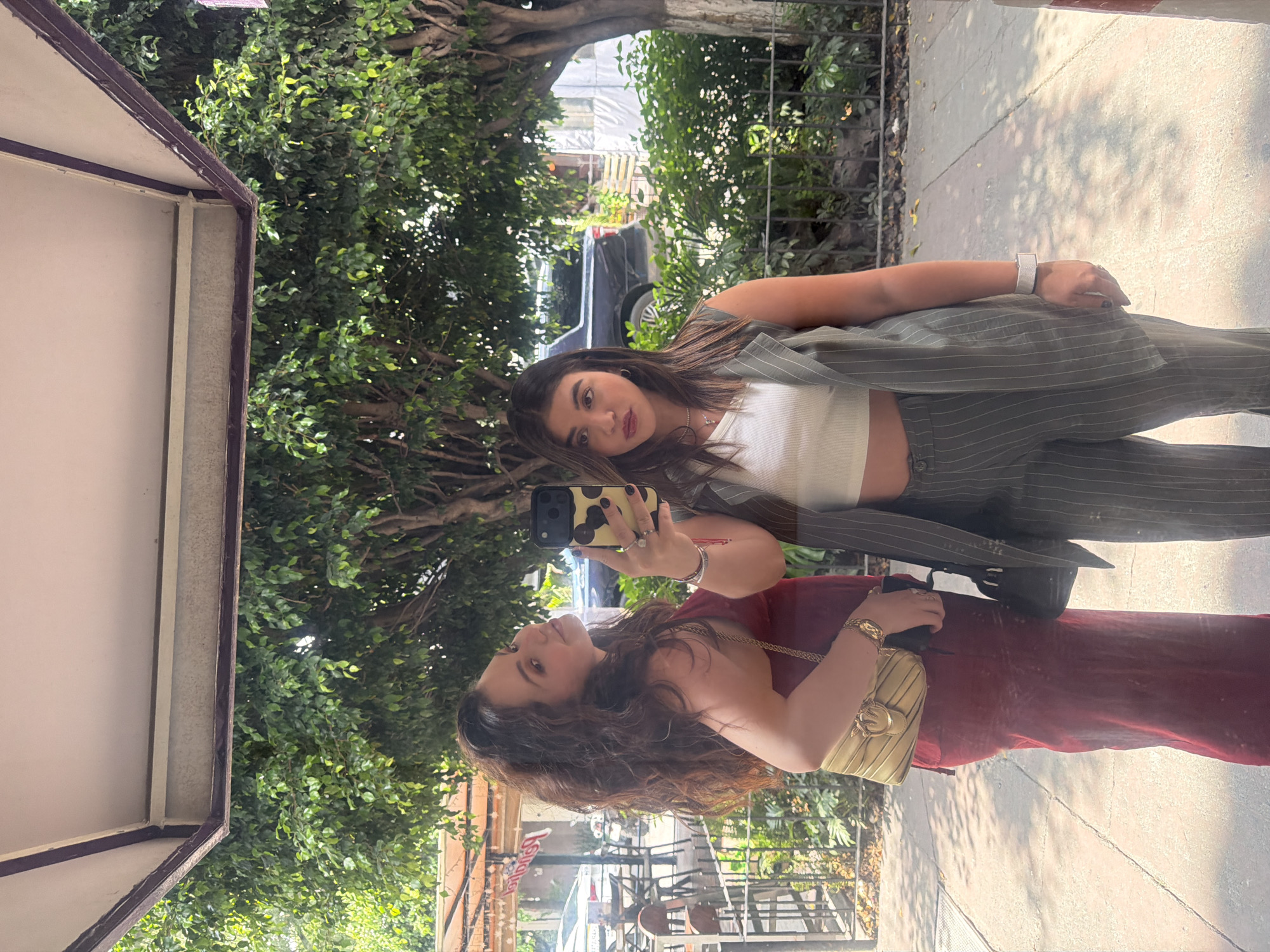 Women take selfies in storefront reflections in Mexico City