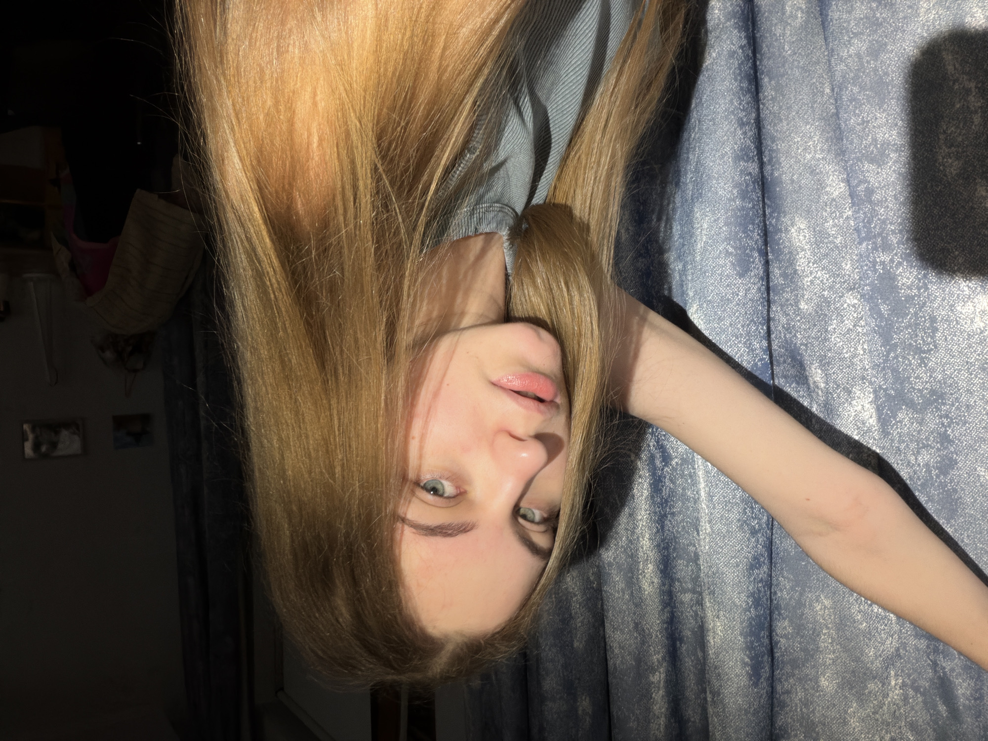 Indoor selfie session in a Dnipro bedroom, blue curtain backdrop