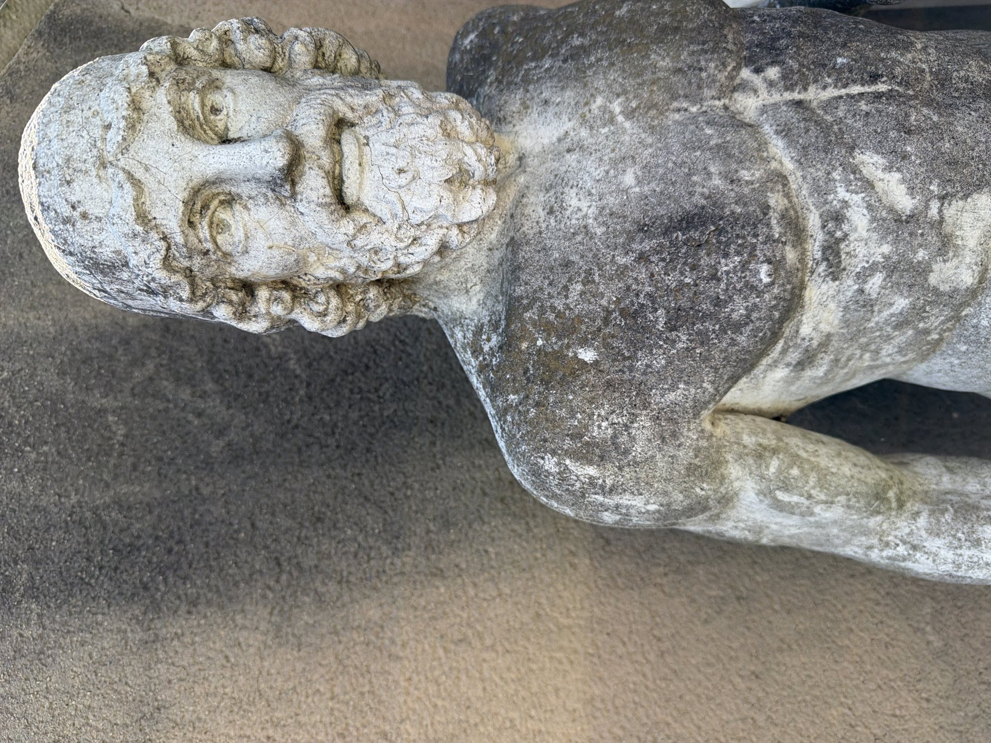 Weathered male statue lies sideways in French town