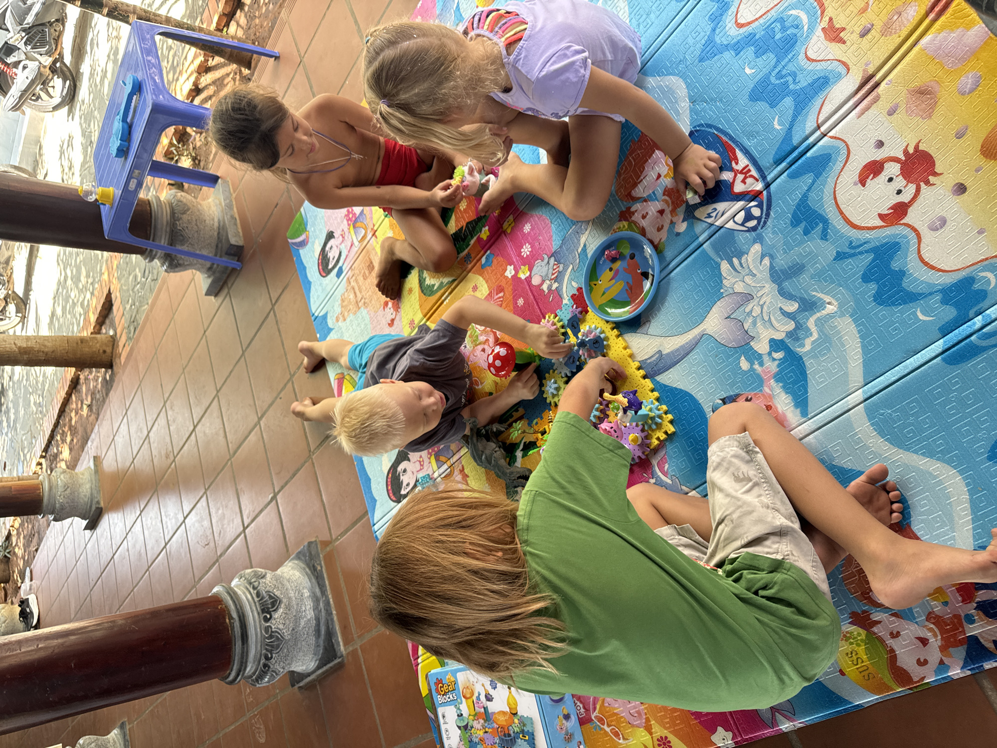 Children play with toys on outdoor mats in Mũi Né