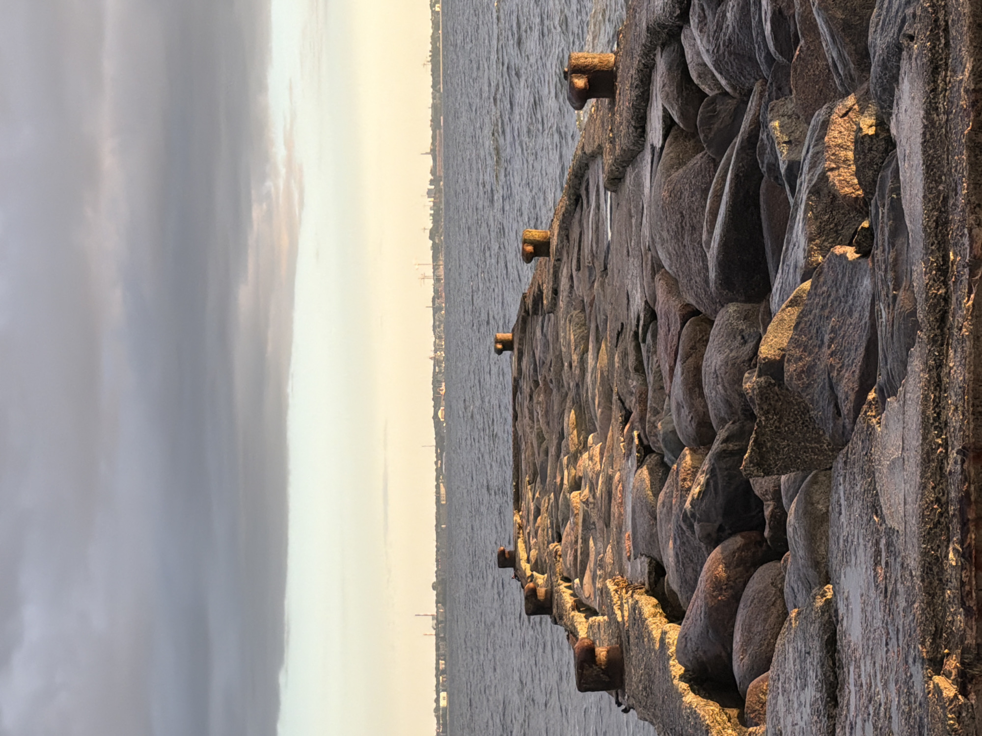 Sunset waves hit Tallinn's rocky shoreline by the pier